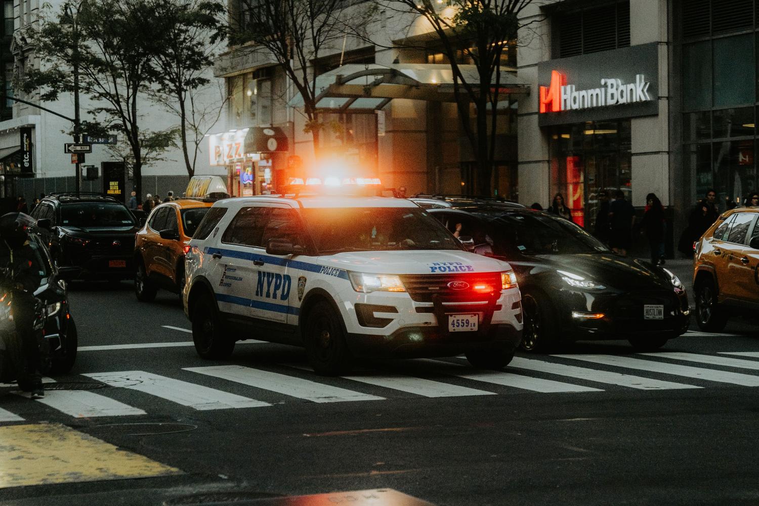 Coche de policía con las luces encendidas en medio del tráfico de una gran ciudad.