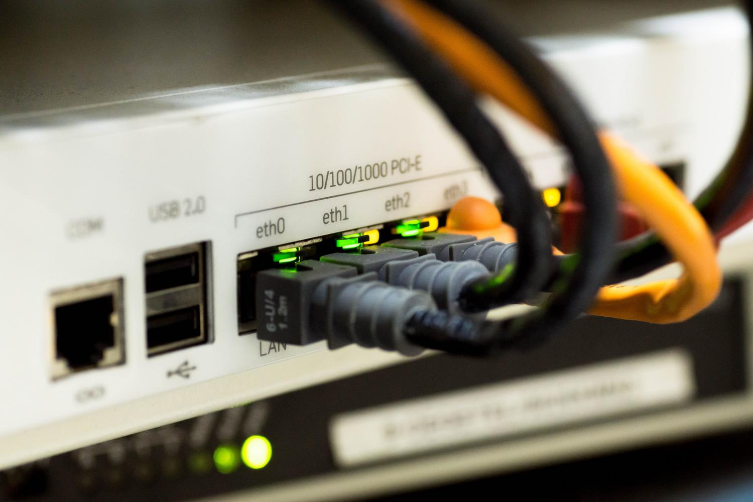 Detalle técnico de puertos Ethernet y cables de red en un router, representando la infraestructura de hardware necesaria.