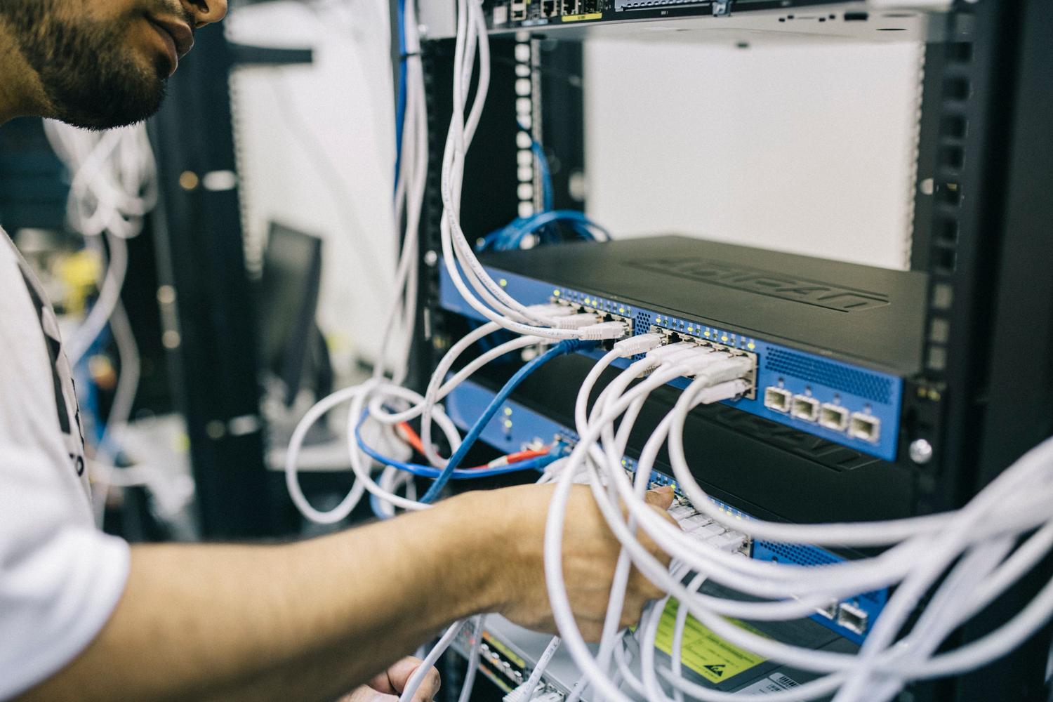 Técnico de IT configurando el cableado de red en un rack de servidores, ideal para la sección de guía de instalación manual.