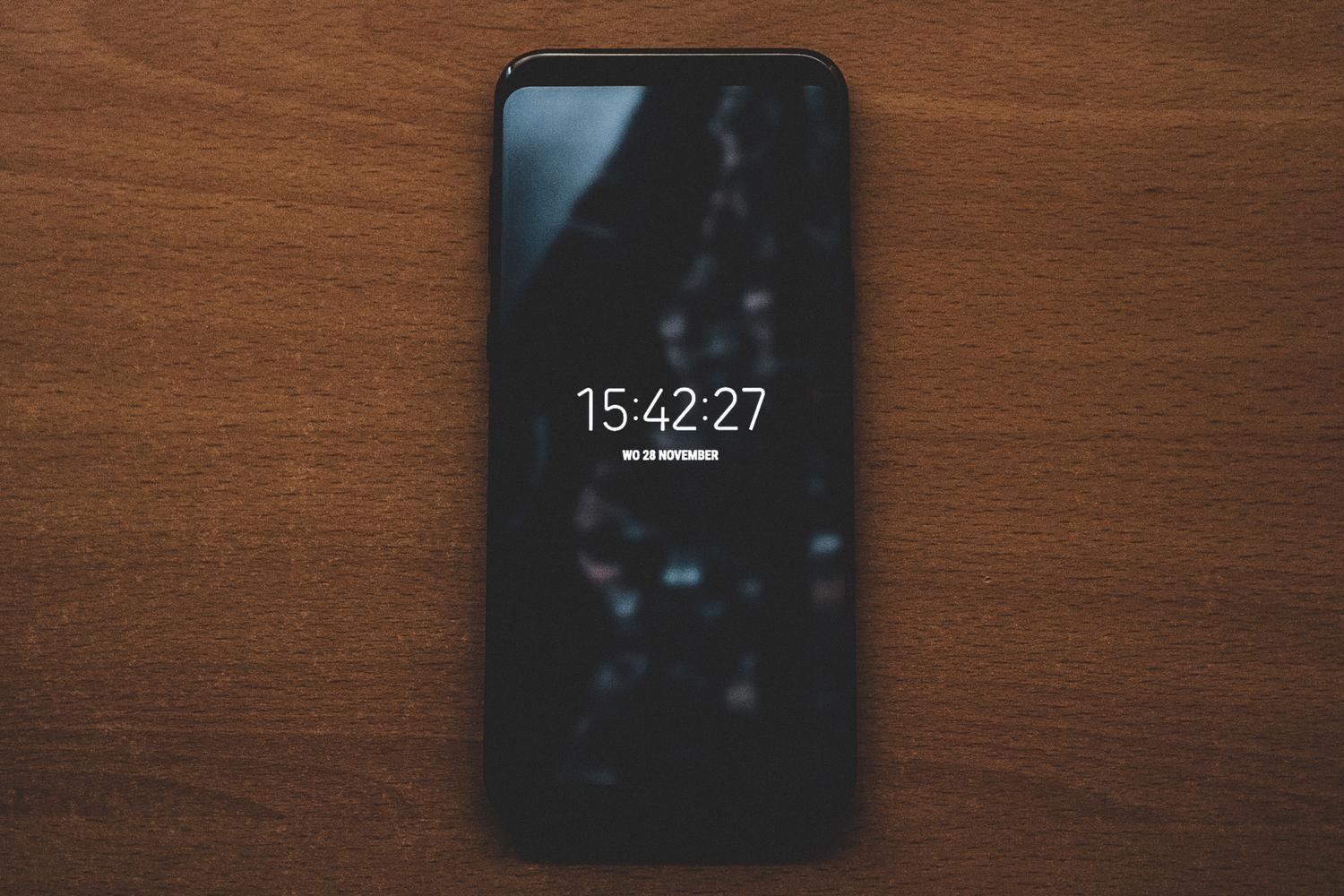 Un teléfono móvil Android dejado sobre una superficie de madera, representando el riesgo de dejar el dispositivo desatendido.