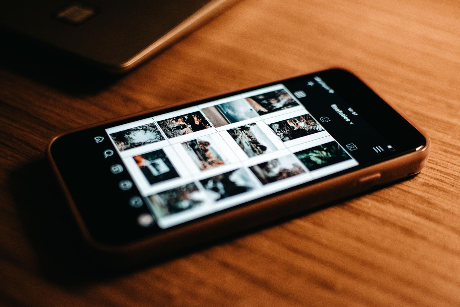 Vista de la galería de fotografías personales en la pantalla de un smartphone sobre una mesa de madera.