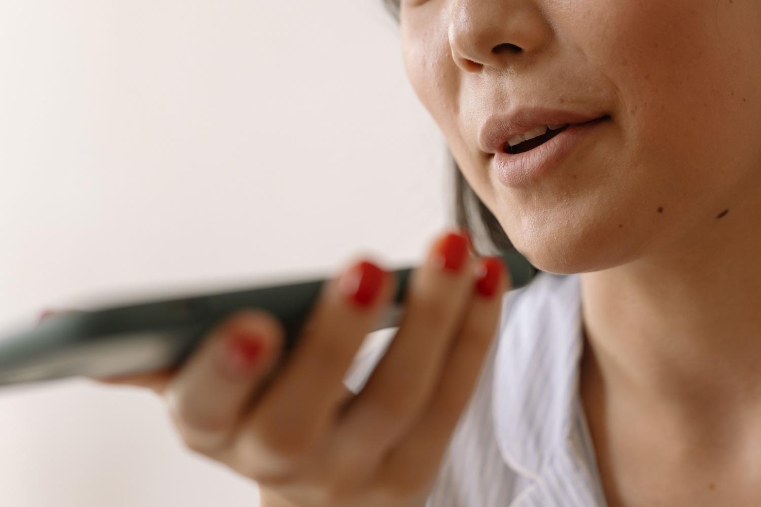 Primer plano de una mujer utilizando comandos de voz en su smartphone, representando el modo de voz de ChatGPT.