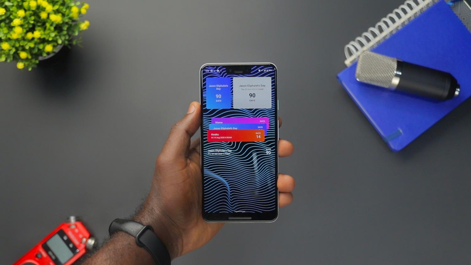 Primer plano de una mano sosteniendo un smartphone con múltiples notificaciones coloridas en pantalla.