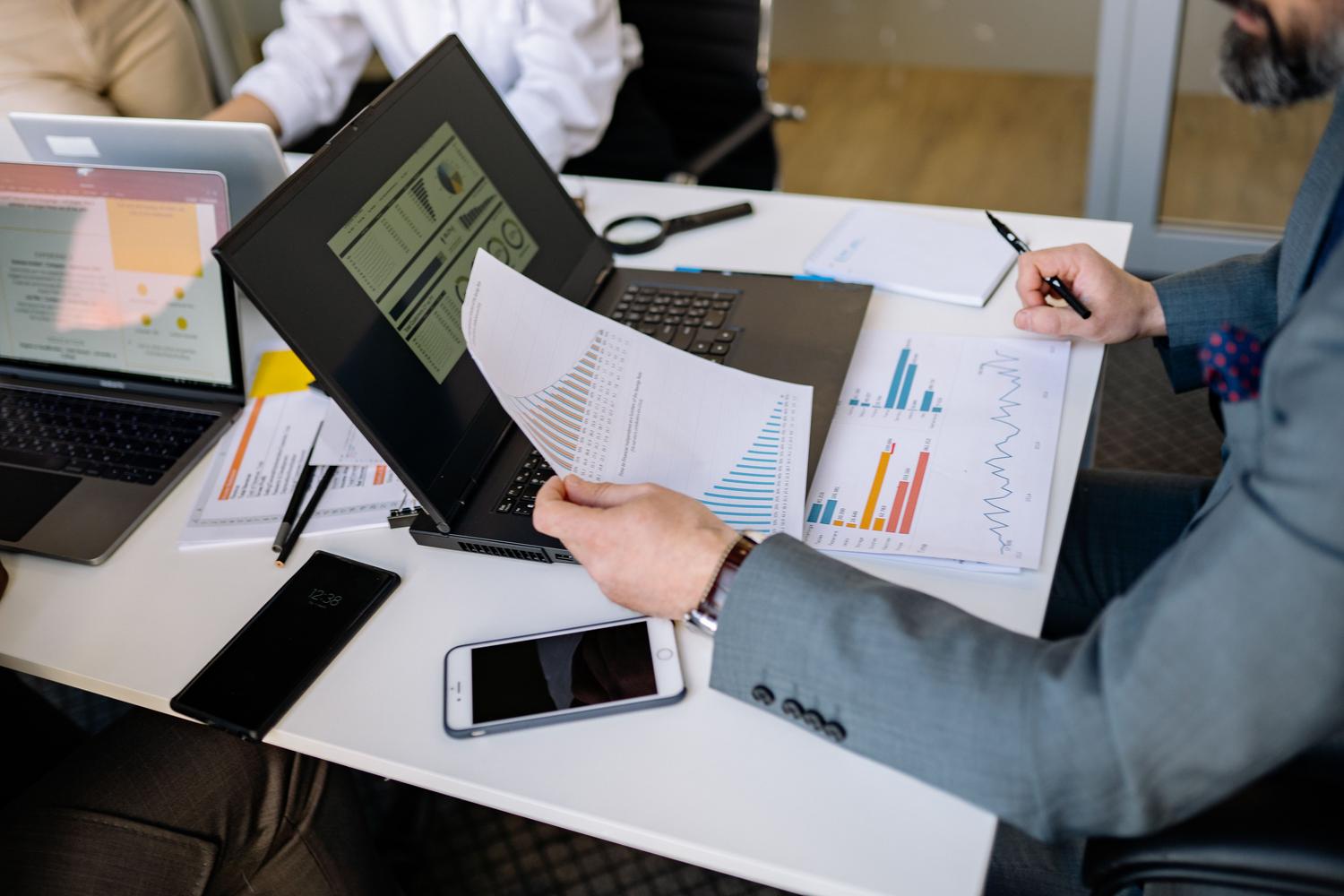Profesionales analizando datos y gráficos en portátiles durante una reunión, ejemplificando los usos prácticos de la IA en el entorno laboral.