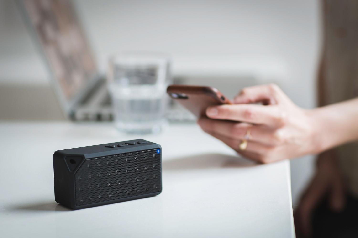 Smartphone conectándose a un altavoz portátil Bluetooth, ideal para ilustrar la conectividad inalámbrica y el audio externo.