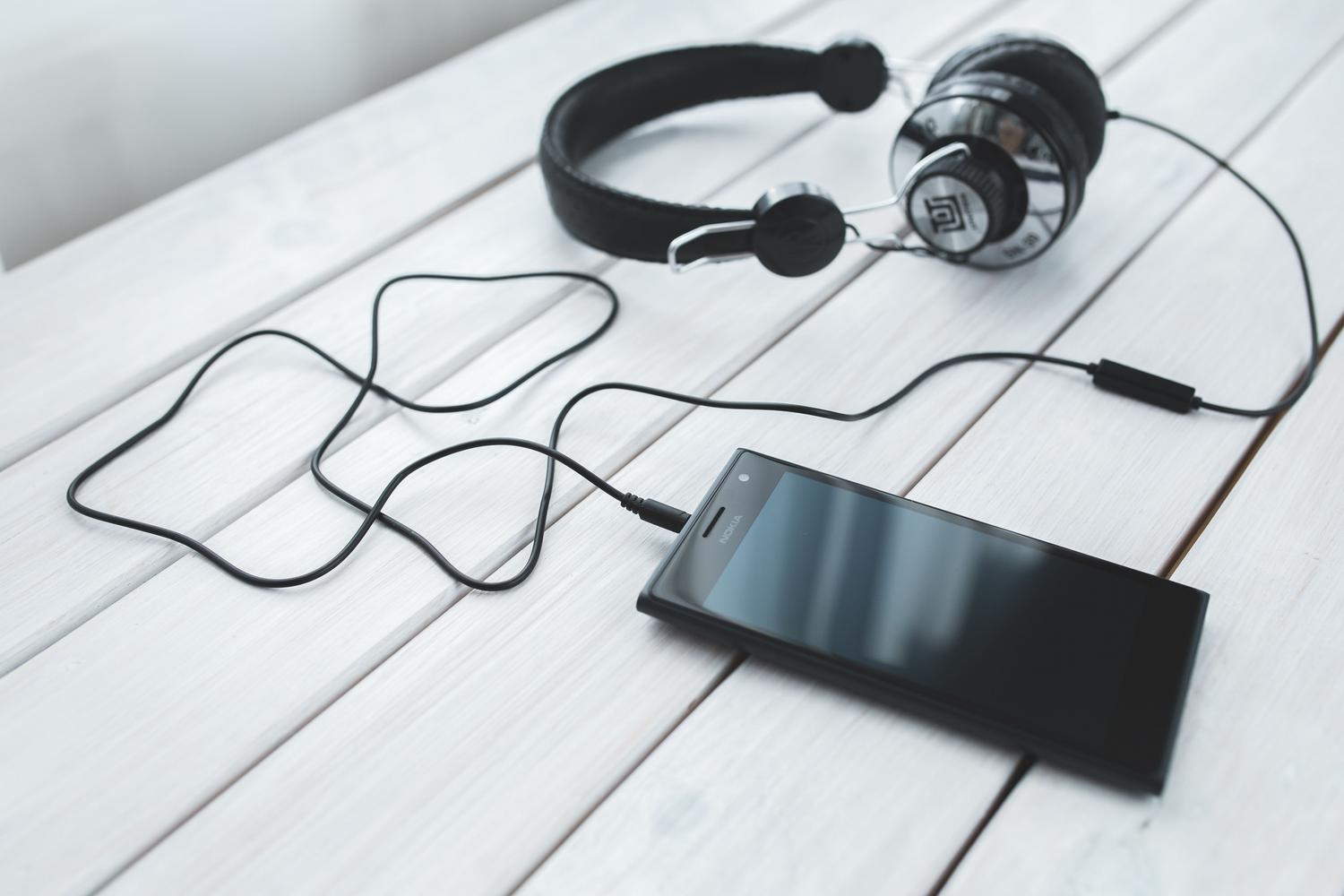 Smartphone conectado a auriculares mediante cable, ilustrando el hardware de audio y la conexión física.