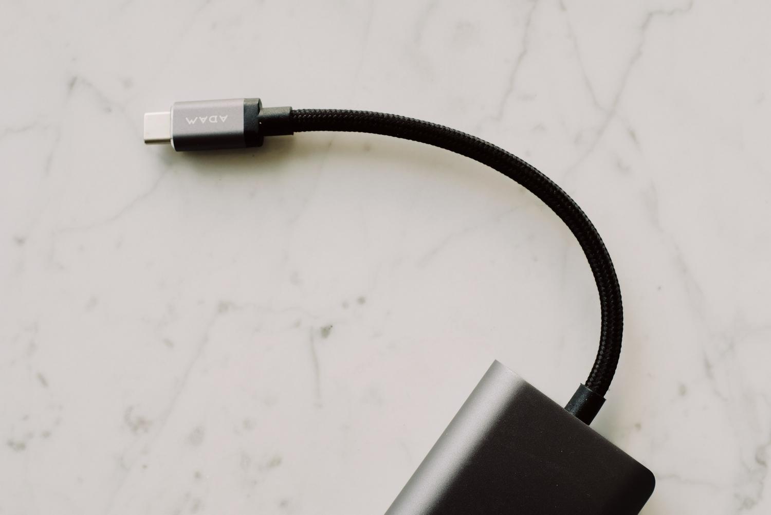 Primer plano de un cable USB-C negro trenzado sobre una superficie de mármol, ideal para ilustrar la transferencia de datos mediante cable.