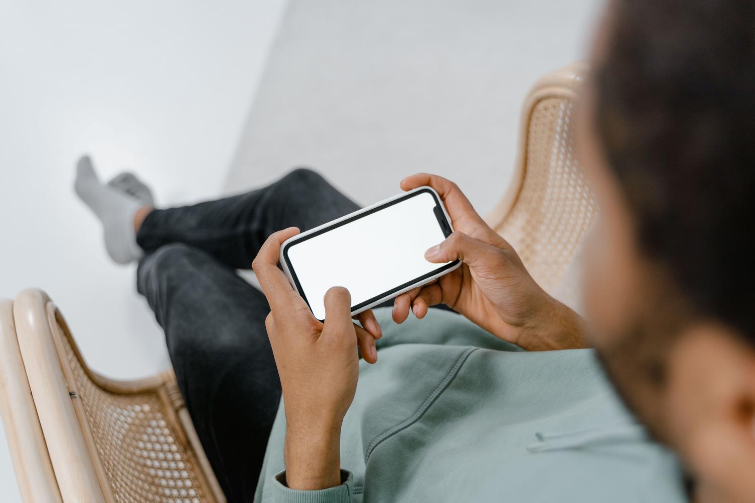 Manos sosteniendo un smartphone moderno, representando el mantenimiento del sistema operativo.