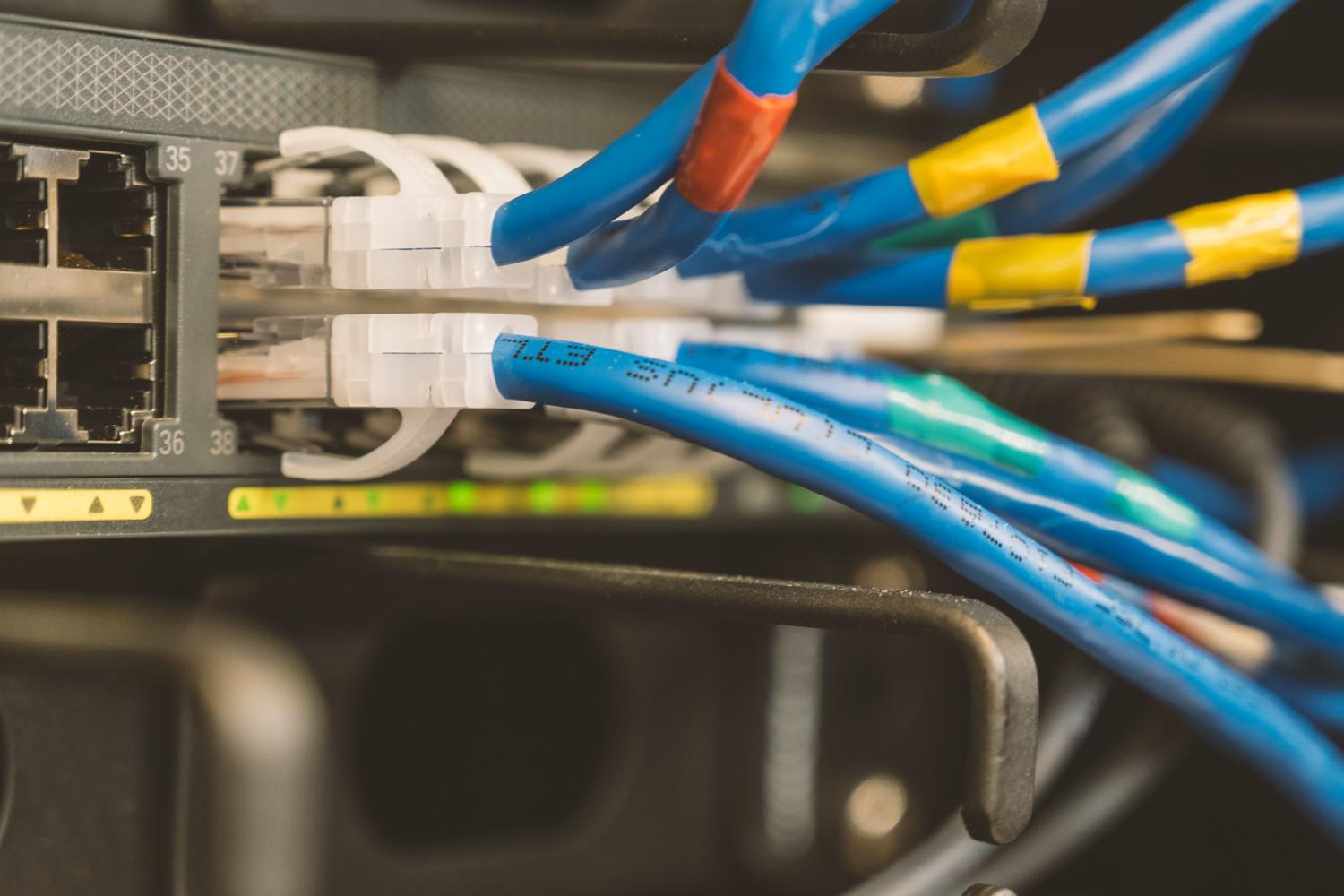 Switch de red corporativo con cables Ethernet azules, ilustrando el hardware de red empresarial y switches veteranos.