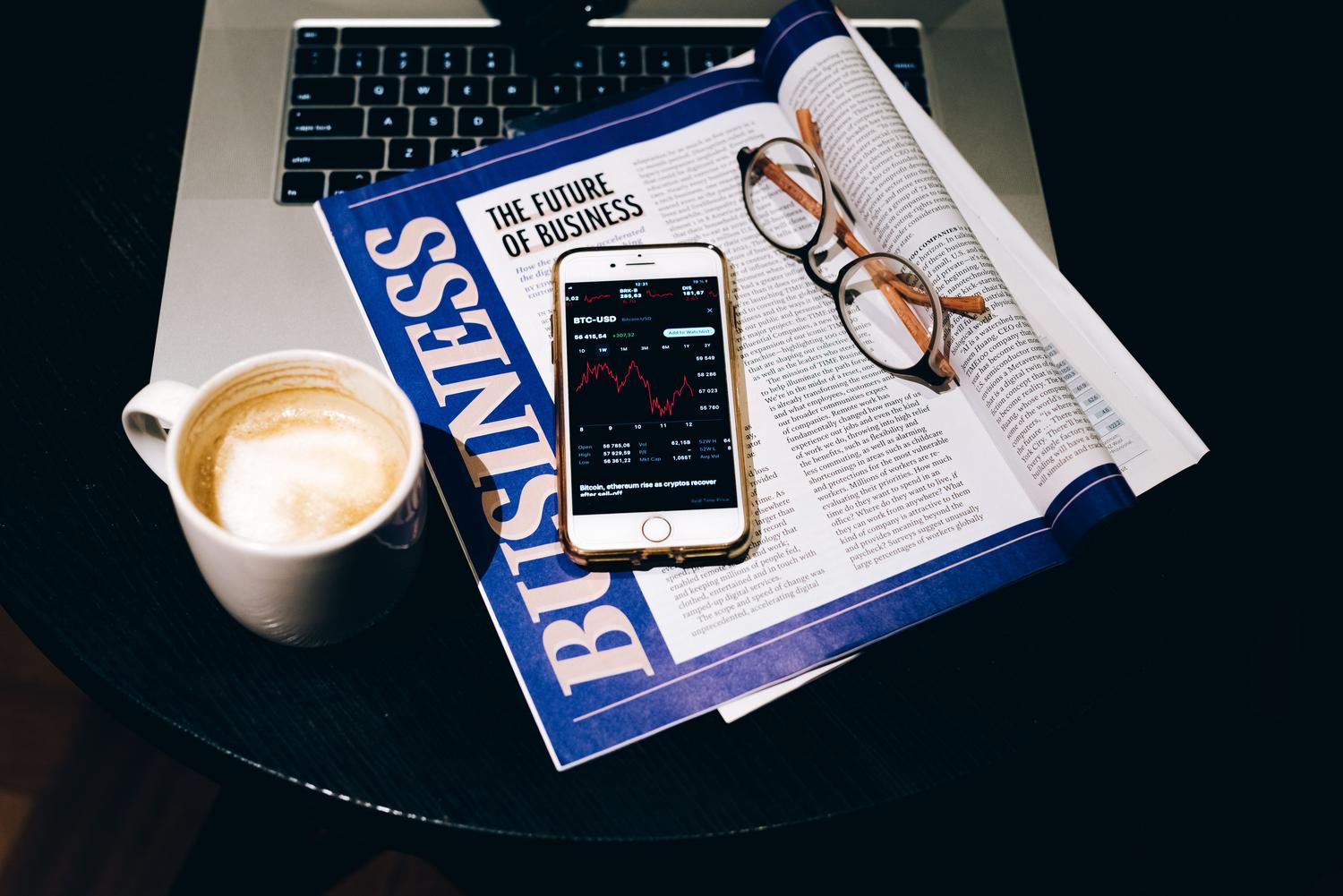 Setup de trabajo con portátil, café y periódico, ideal para ilustrar el concepto de newsletter y consumo de contenido.