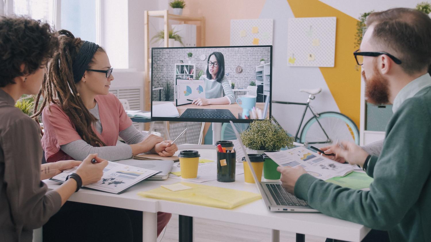 Equipo creativo colaborando en una oficina moderna utilizando herramientas digitales para el trabajo en equipo.