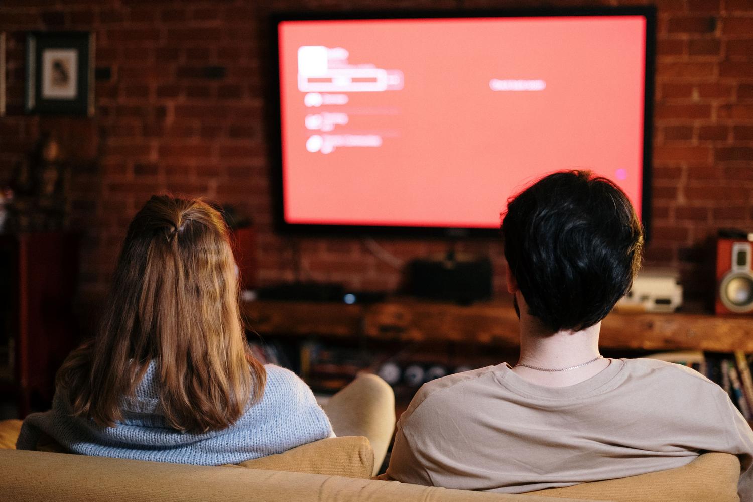 Pareja relajada en un sofá viendo una serie en su salón, representando el objetivo final de disfrutar de contenidos sin problemas de compatibilidad.