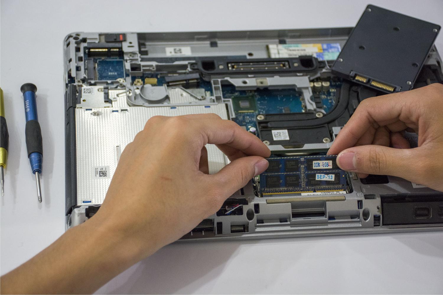 Técnico manipulando componentes internos de un ordenador portátil, ilustrando el mantenimiento físico y la revisión de hardware de almacenamiento.