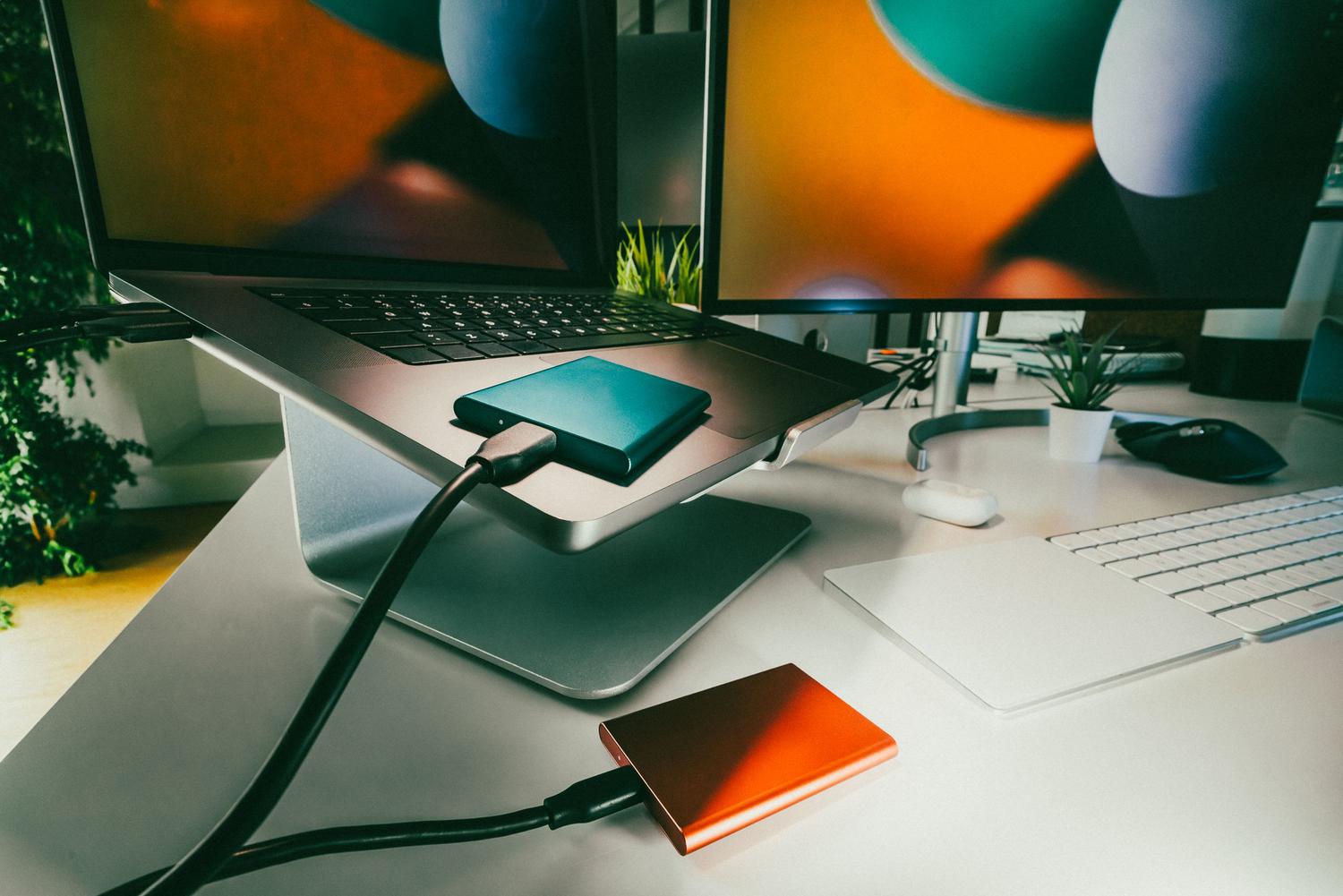 Entorno de oficina moderno con laptop y discos duros externos conectados, representando la importancia de realizar copias de seguridad preventivas.