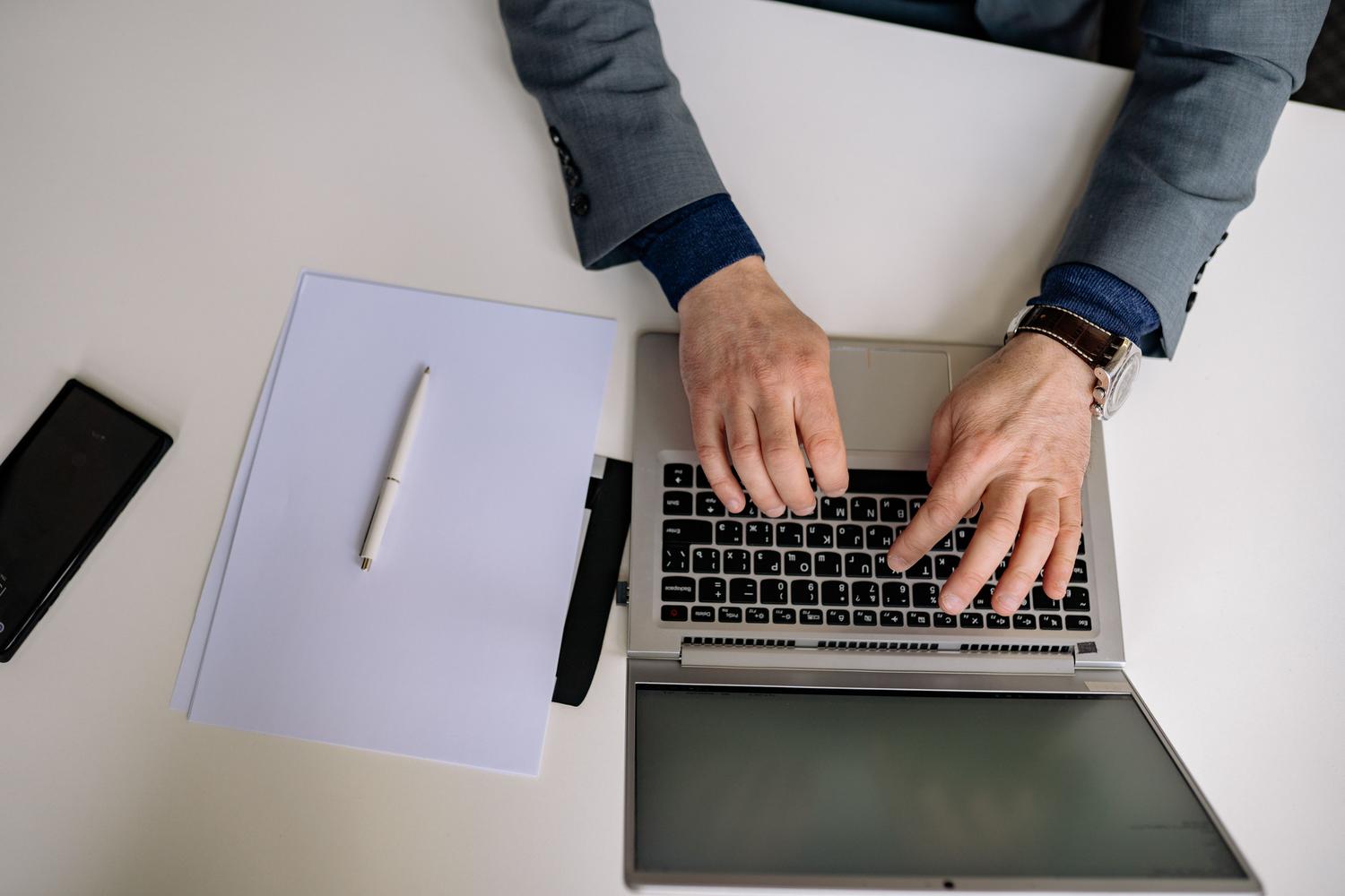 Hombre profesional trabajando con un portátil en un entorno de oficina, representando el contexto corporativo donde se utilizan herramientas de productividad como Microsoft Office.