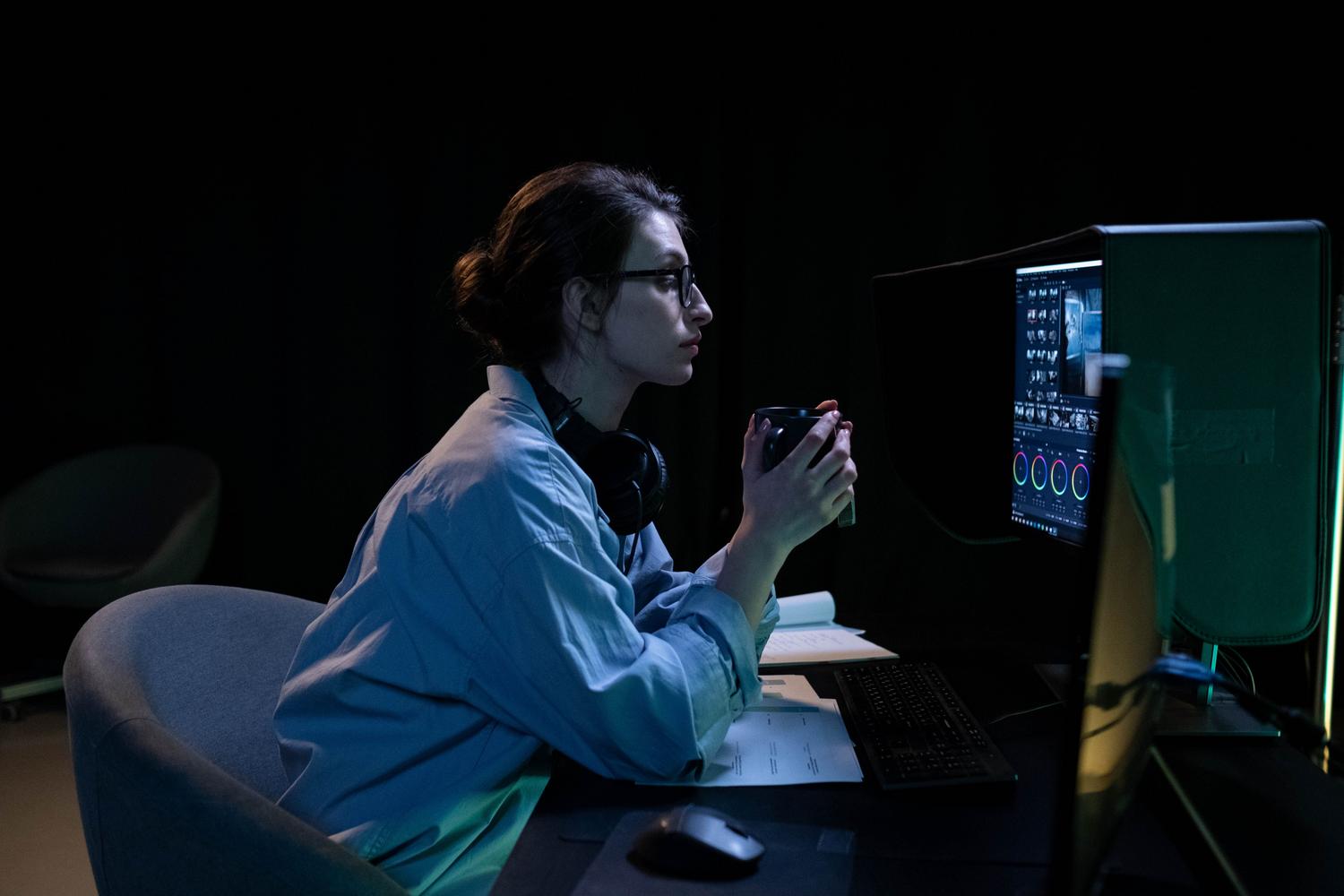Persona trabajando concentrada frente a un monitor en una habitación con poca luz, perfecta para ilustrar el uso de filtros de brillo o luz nocturna.