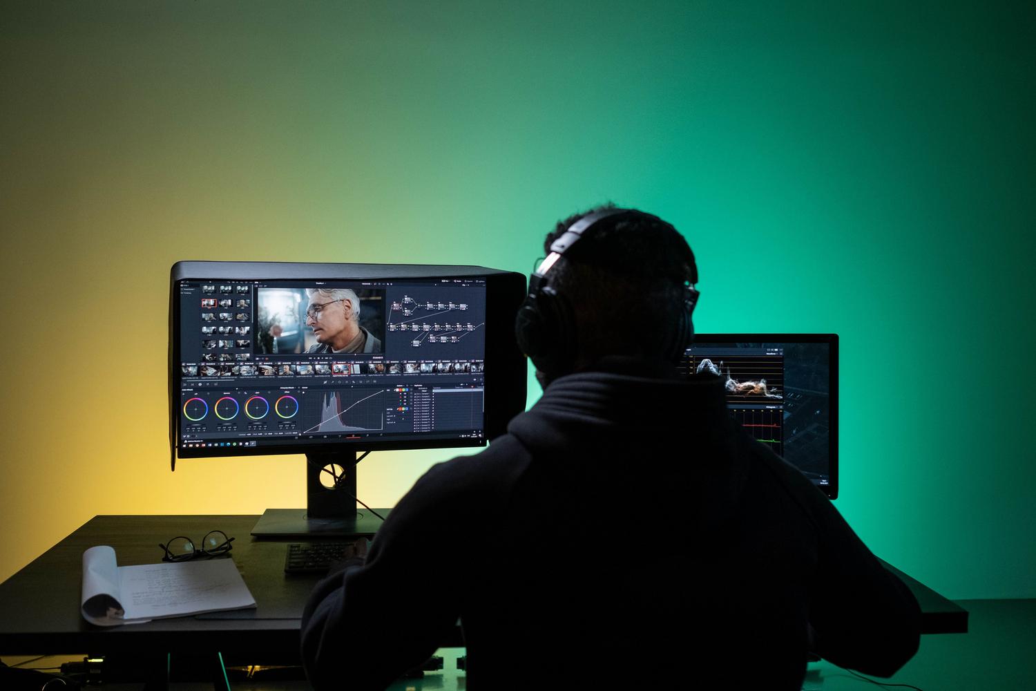 Editor de vídeo profesional trabajando con doble monitor, enfocándose en la corrección de color y calibración de pantalla.