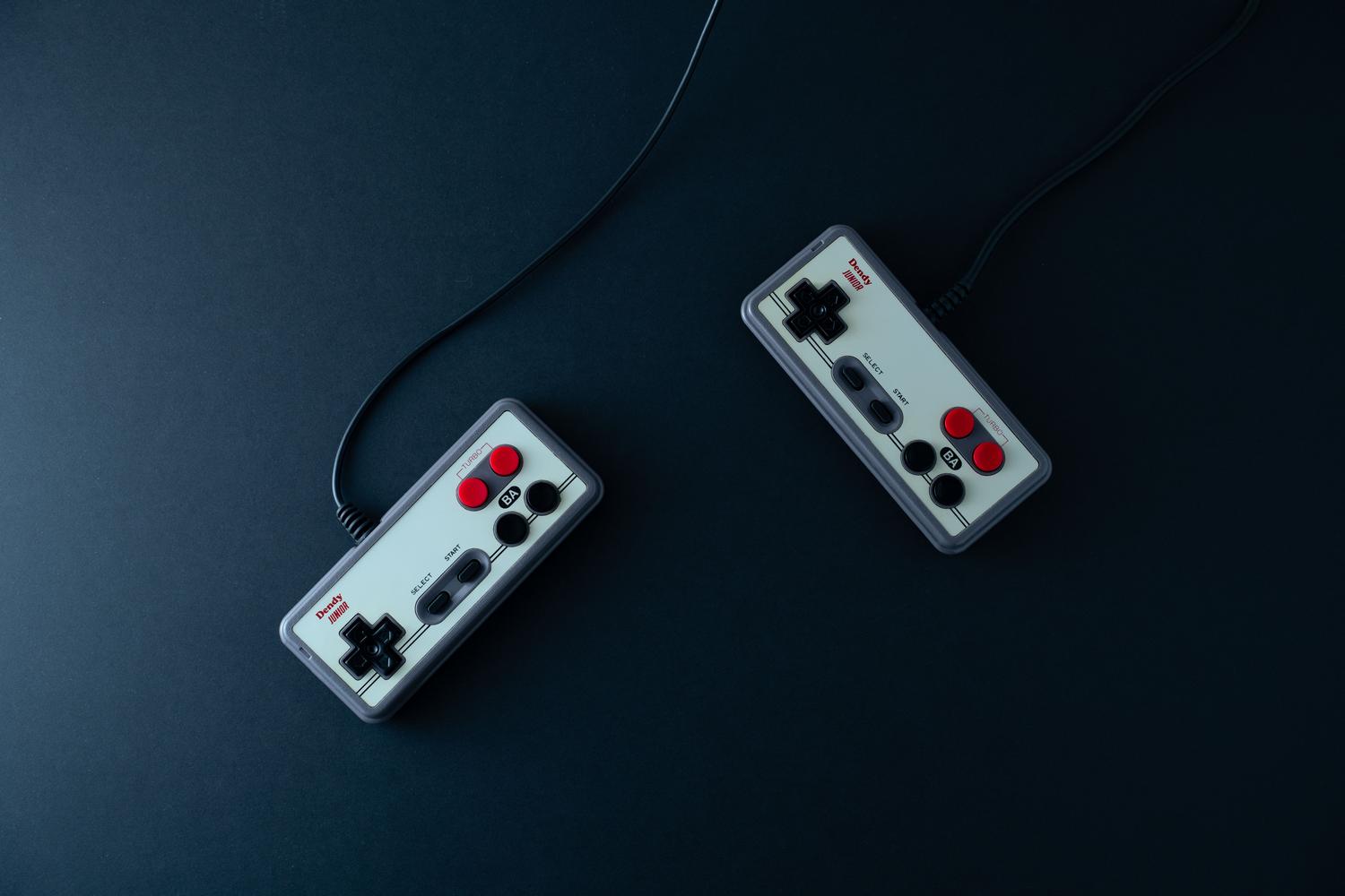 Dos mandos de videojuegos retro estilo NES sobre un fondo oscuro, representando los inicios del gaming.