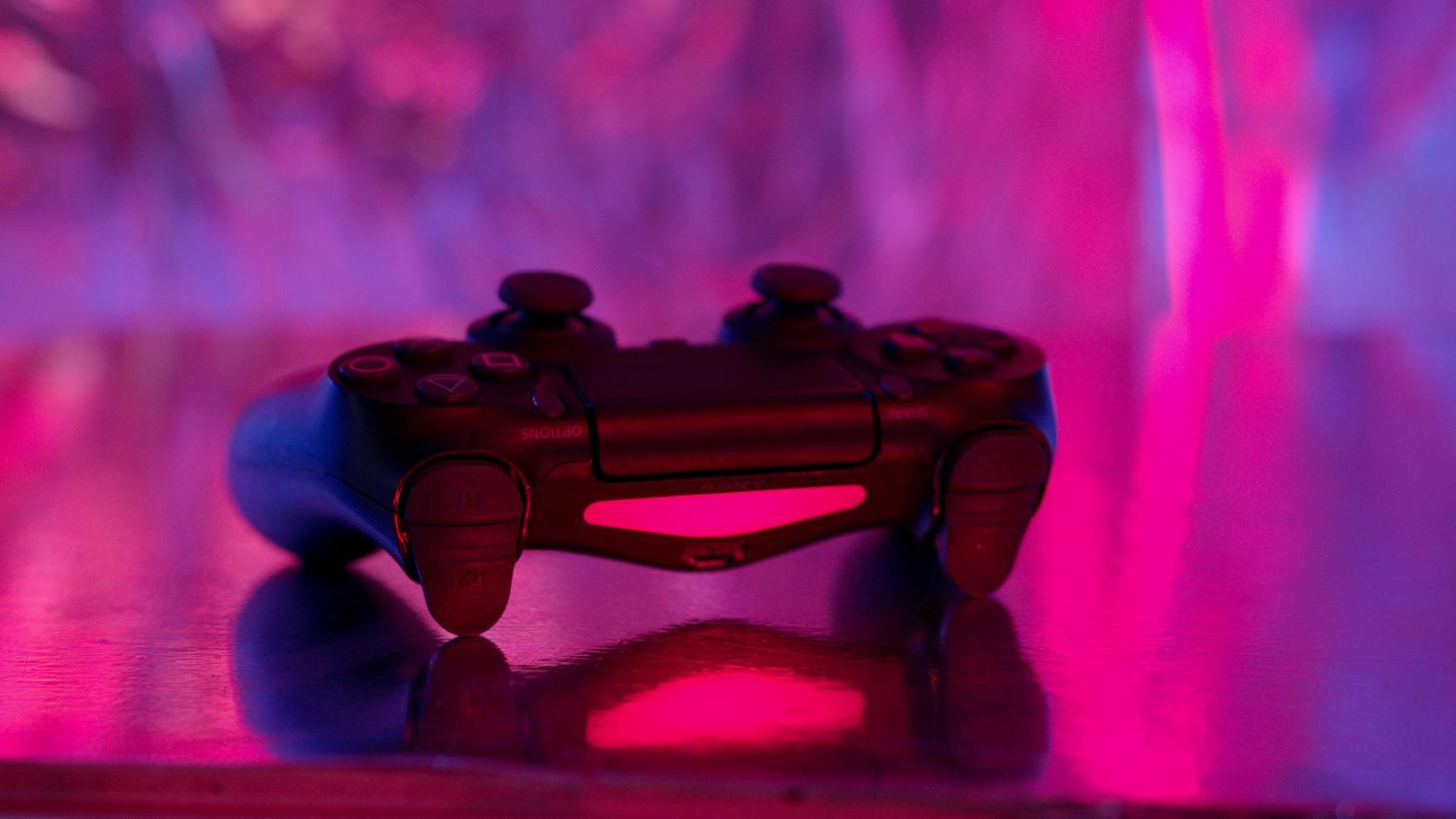 Mando de PlayStation 4 con iluminación neon rosa y púrpura, destacando la estética gamer moderna.