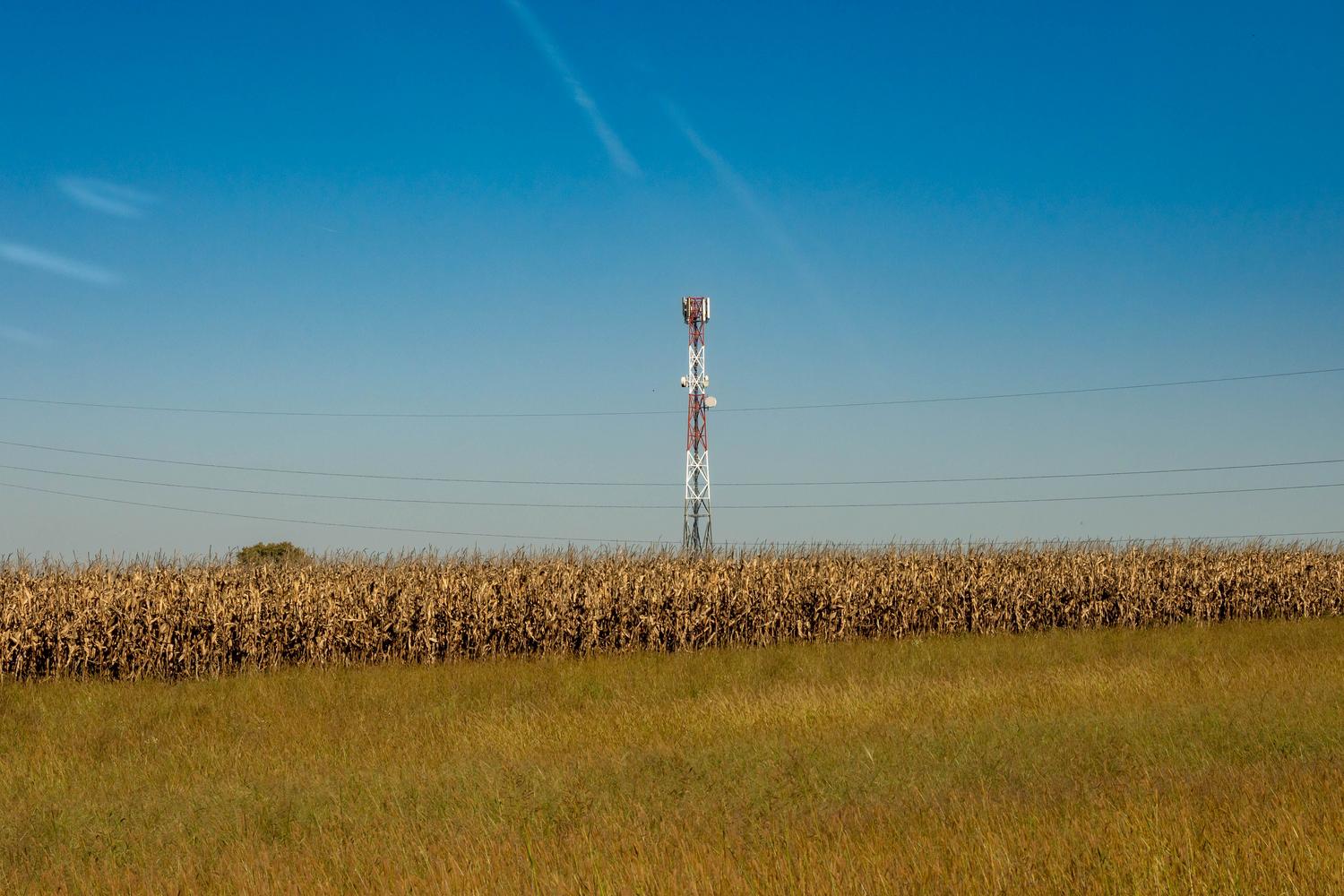 Una torre de comunicaciones celular en un campo rural bajo un cielo azul, representando la infraestructura de red que determina la cobertura. Una torre de comunicaciones celular en un campo rural bajo un cielo azul, representando la infraestructura de red que determina la cobertura.
