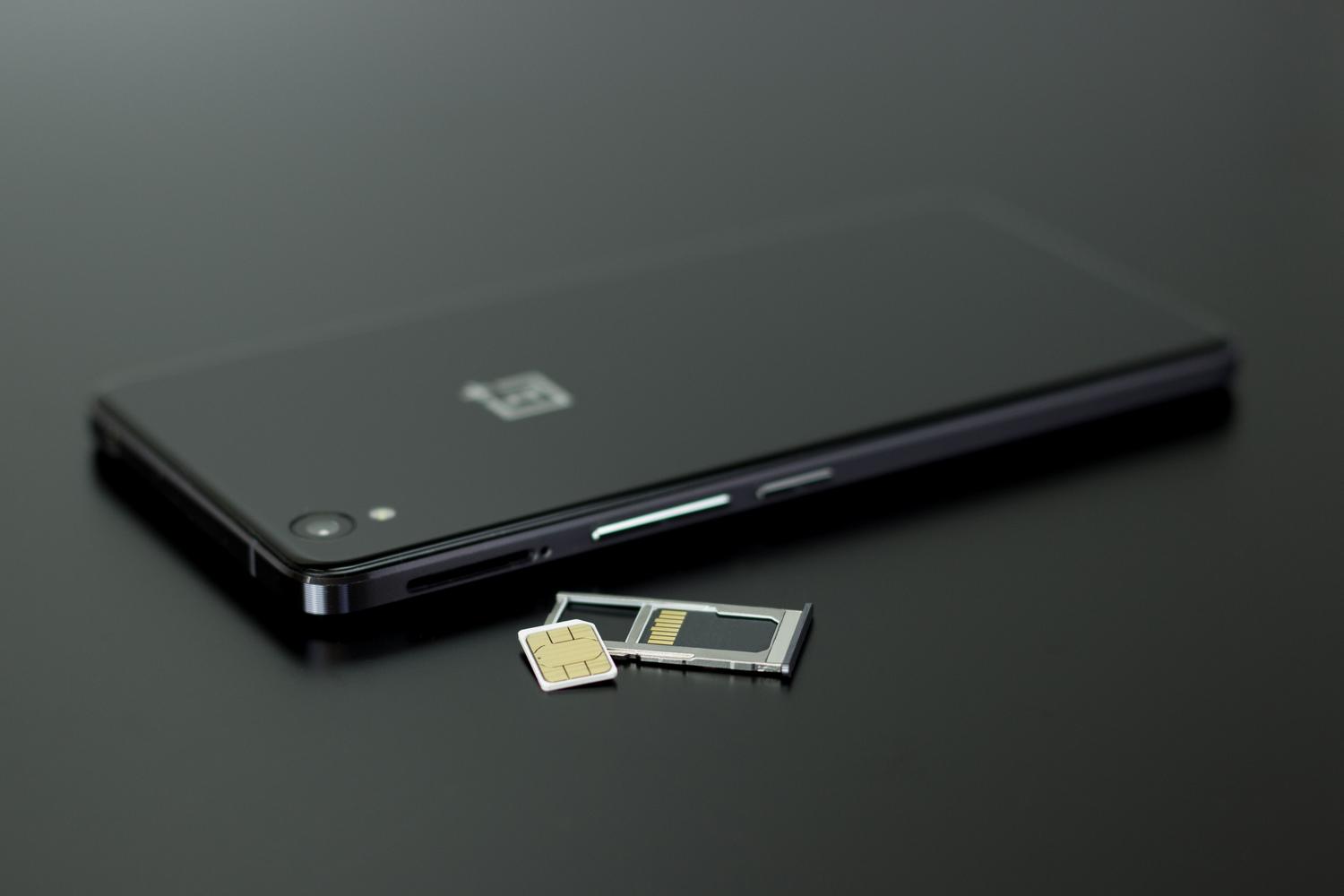 Smartphone moderno junto a su bandeja y una tarjeta SIM física, representando la conectividad tradicional.