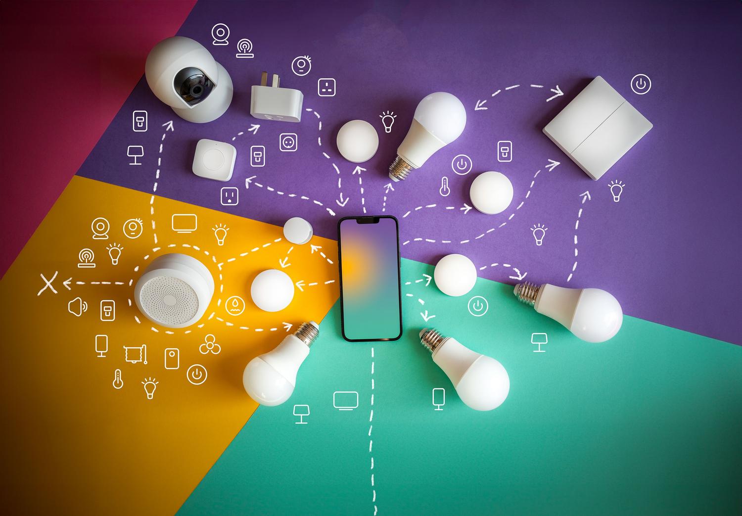 Vista cenital de diversos dispositivos inteligentes para el hogar y un smartphone, ilustrando la interconectividad del ecosistema IoT.