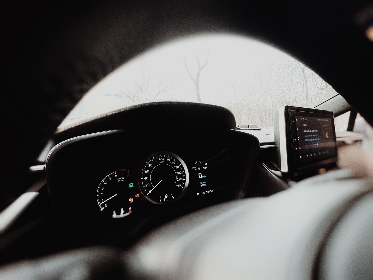 Panel de control digital de un coche moderno con pantalla táctil y velocímetro, ilustrando la conectividad y el transporte inteligente.