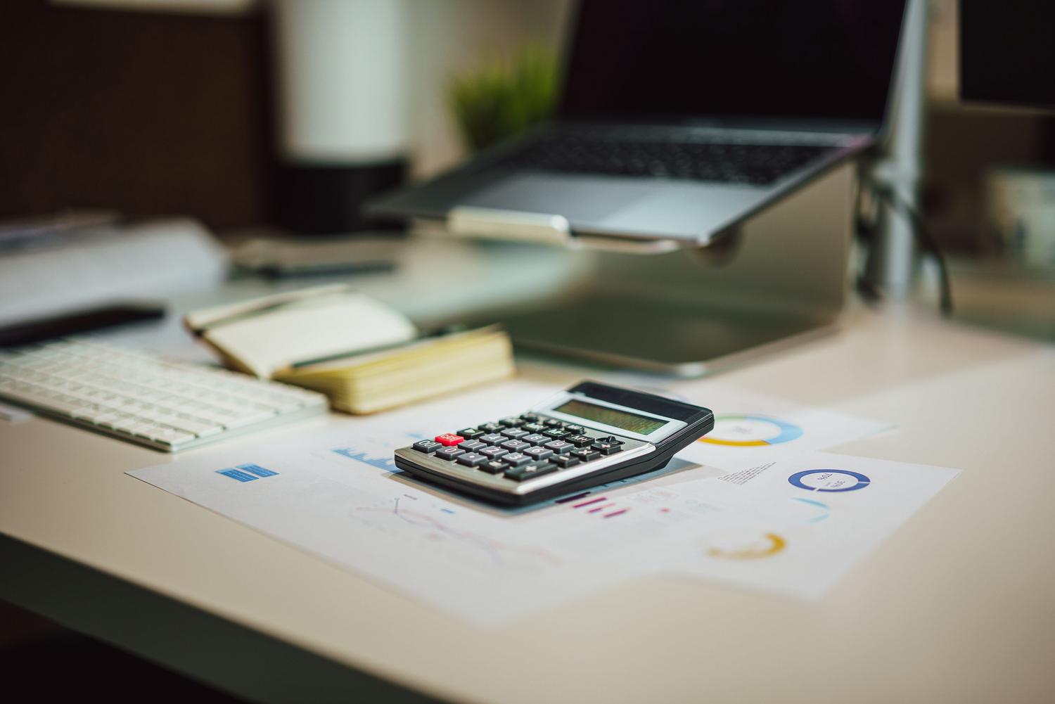 Espacio de trabajo moderno con portátil, calculadora y documentos, perfecto para la sección de operaciones matemáticas en Excel.