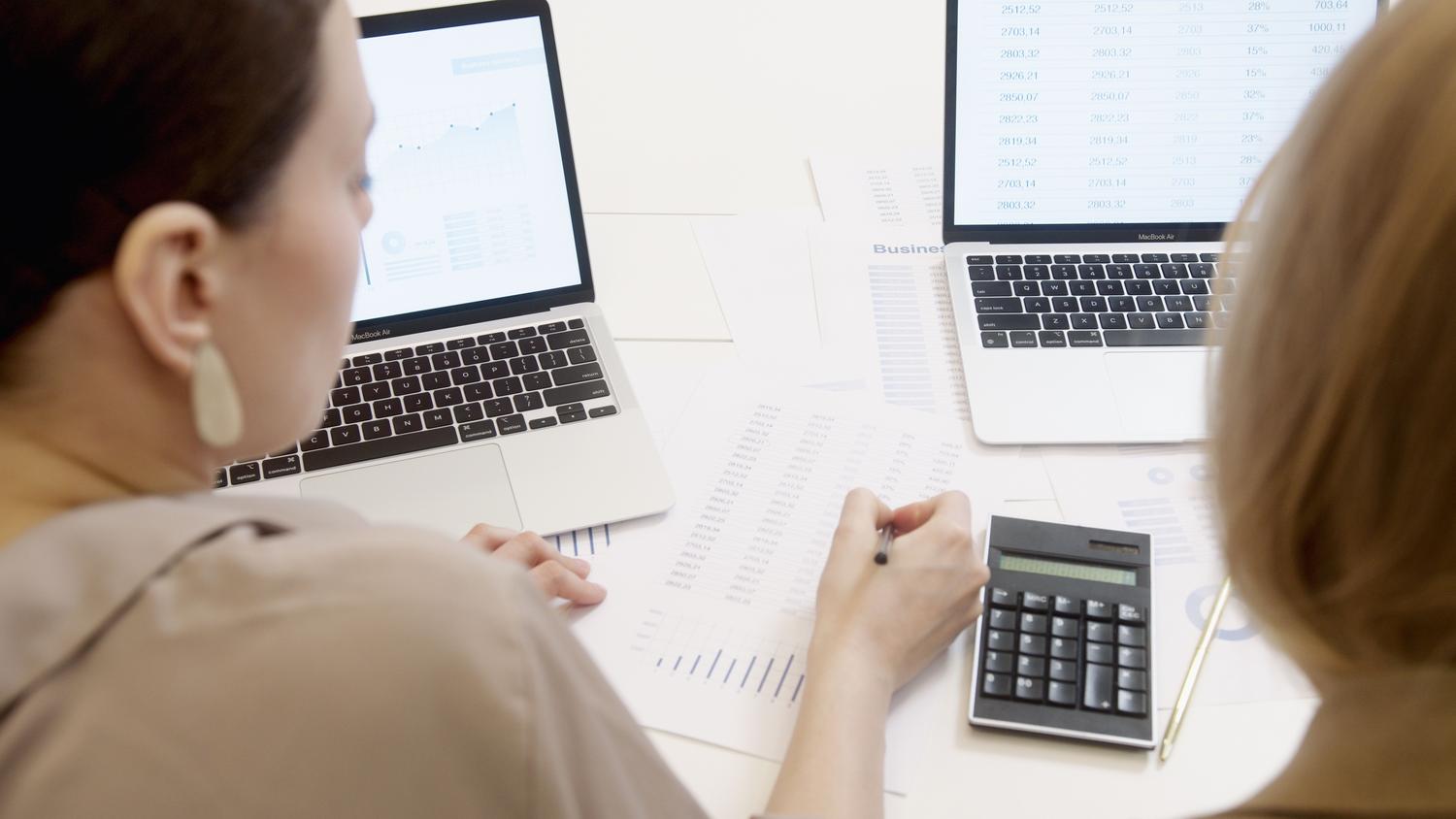 Profesionales analizando datos empresariales y gráficos en ordenadores portátiles en un entorno de oficina.