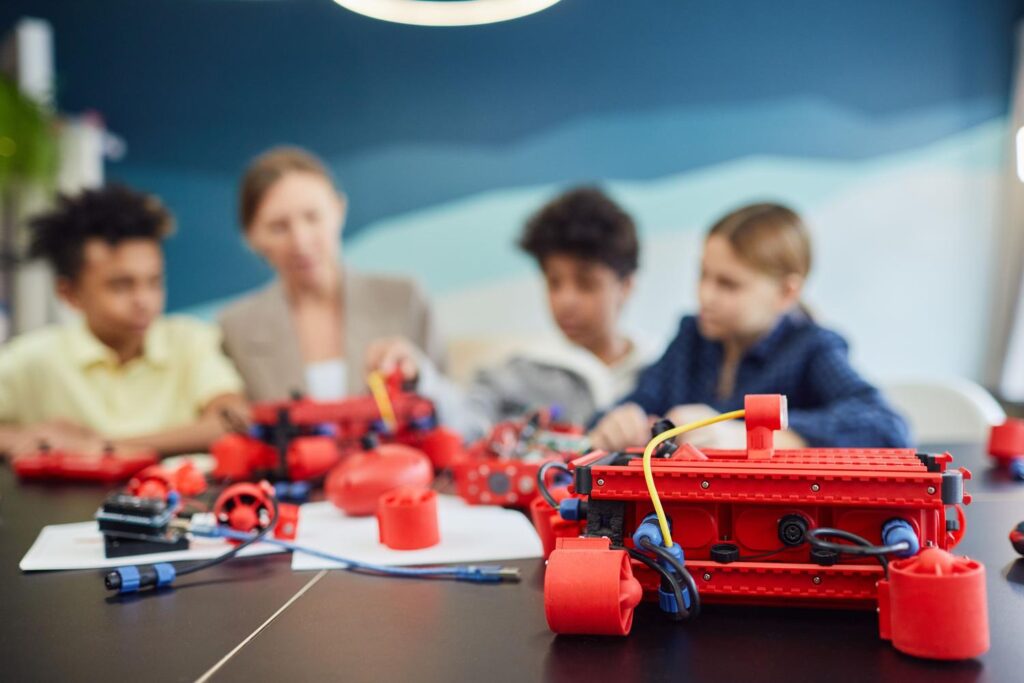 Grupo de niños y una profesora trabajando colaborativamente en un proyecto de robótica educativa en un aula STEM.