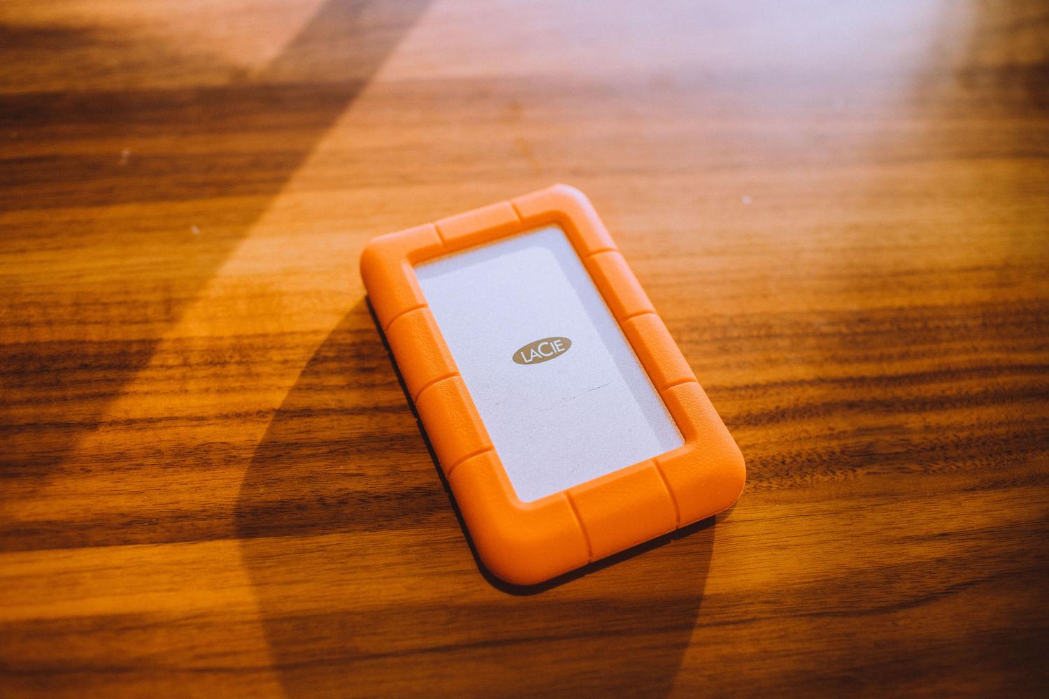 Disco duro externo portátil sobre una mesa de madera, como ejemplo de dispositivo sencillo para copias de seguridad personales.