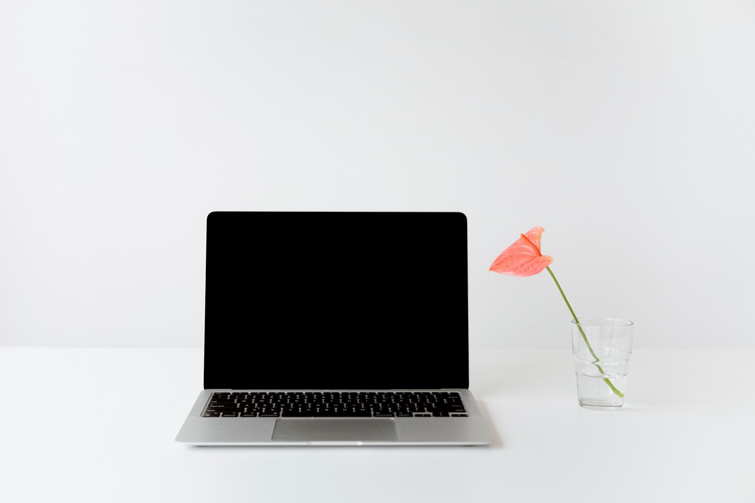 Espacio de trabajo minimalista con un ordenador portátil plateado sobre un escritorio blanco, transmitiendo limpieza y profesionalidad.