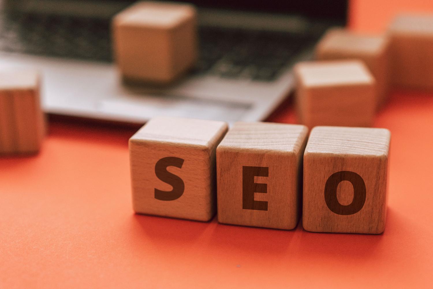 Bloques de madera con las siglas SEO sobre el teclado de un portátil, simbolizando el posicionamiento orgánico.