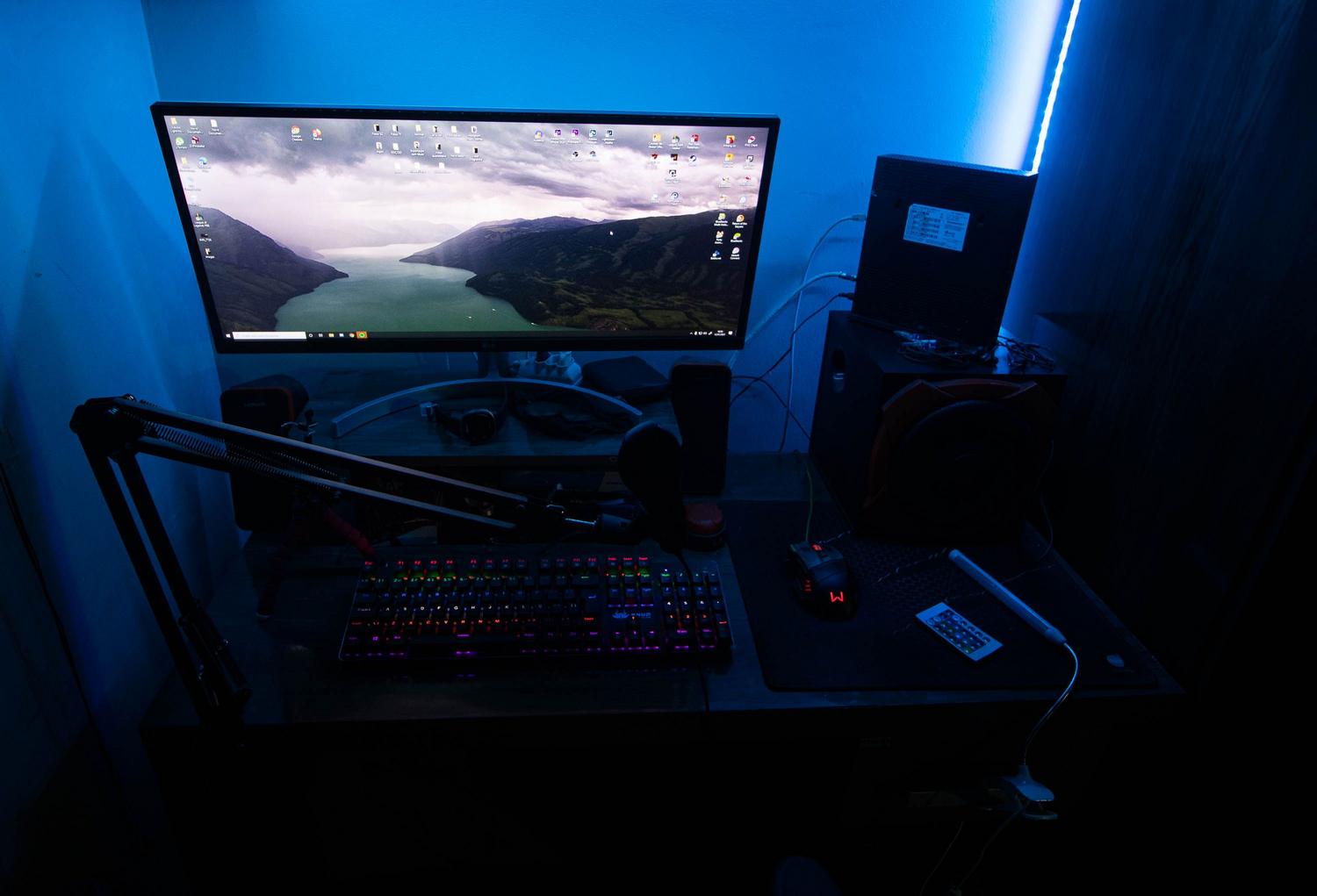 Escritorio de gaming con iluminación LED azul y periféricos tecnológicos.
