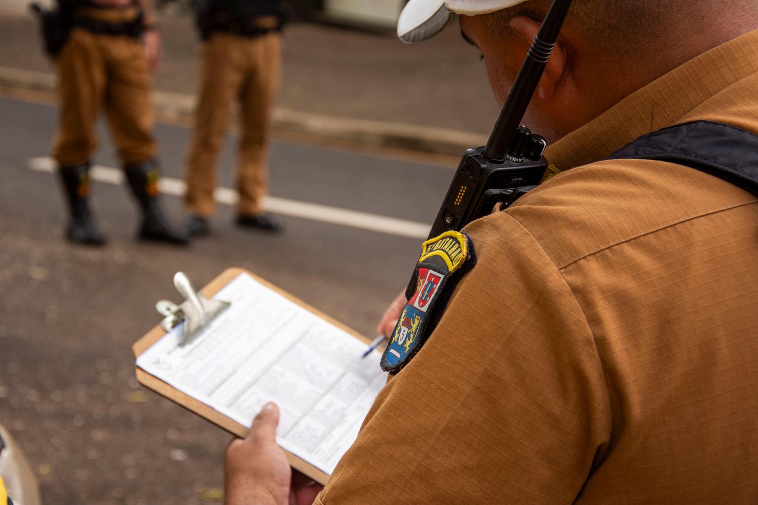 Agente de tráfico escribiendo una sanción en una tabla portapapeles, simbolizando la recepción de una multa.