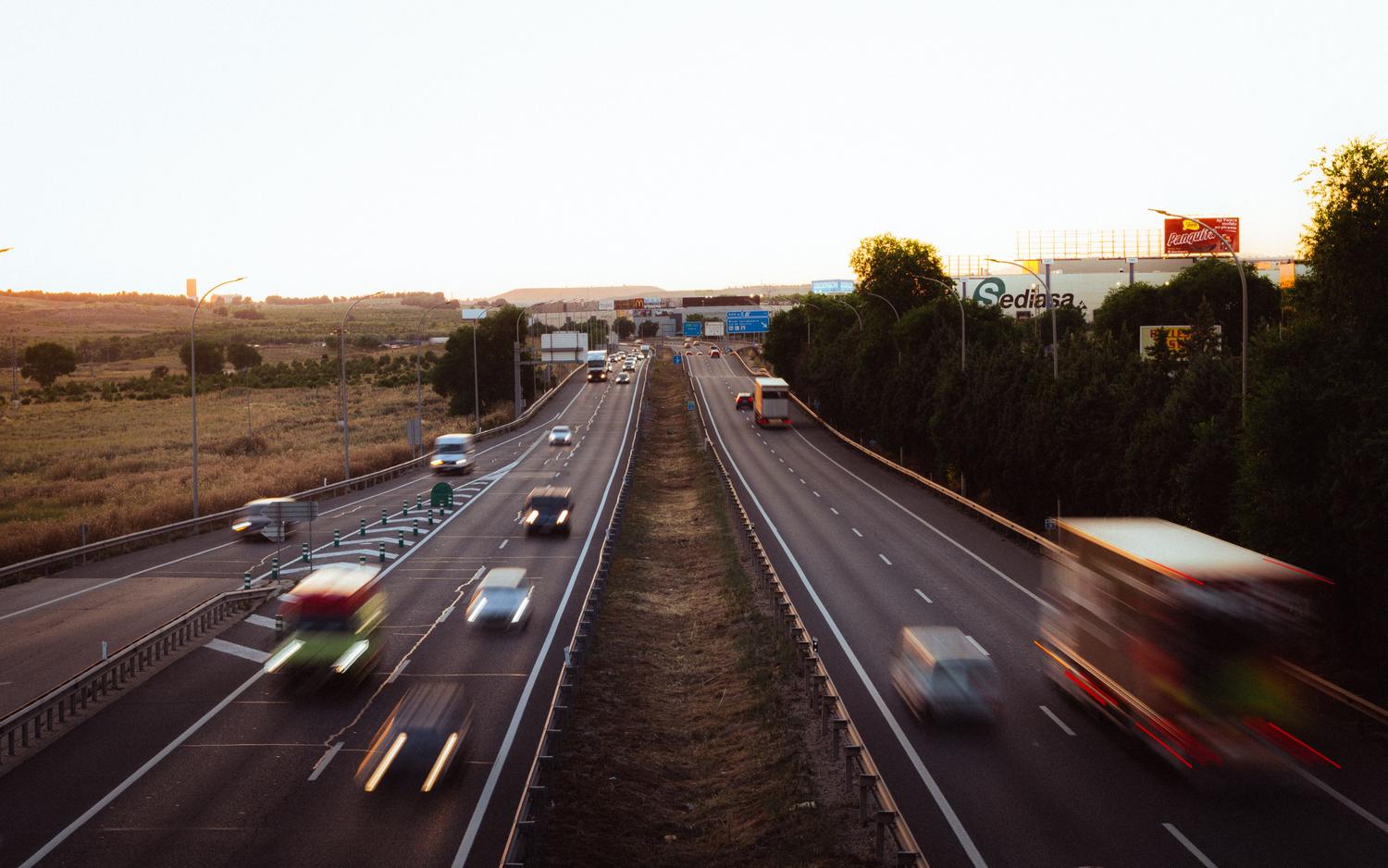 Vista aérea de una autopista con tráfico intenso en Madrid, España, al atardecer, proporcionando contexto geográfico.