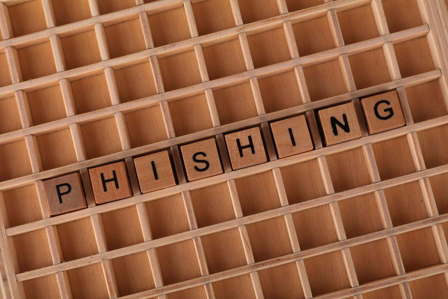 Letras de madera formando la palabra 'Phishing' sobre un tablero, ilustrando el concepto de suplantación de identidad y ataques de ingeniería social.