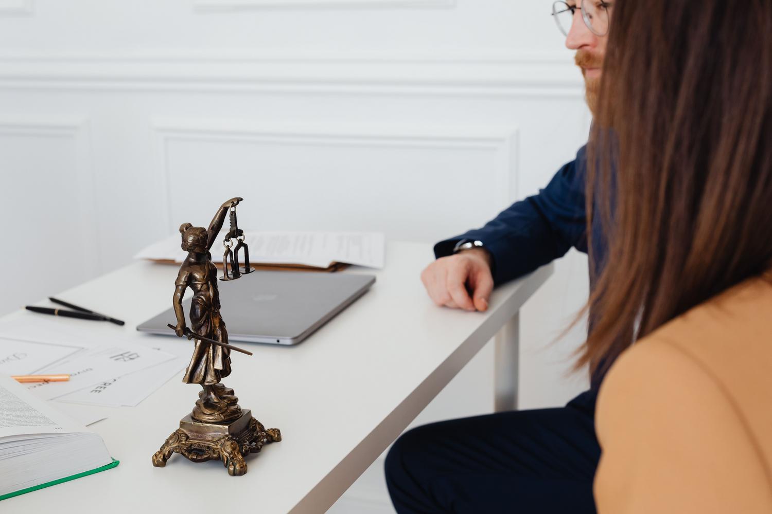 Consulta legal profesional con abogados y la estatua de la Justicia, subrayando la necesidad de asesoramiento humano experto.