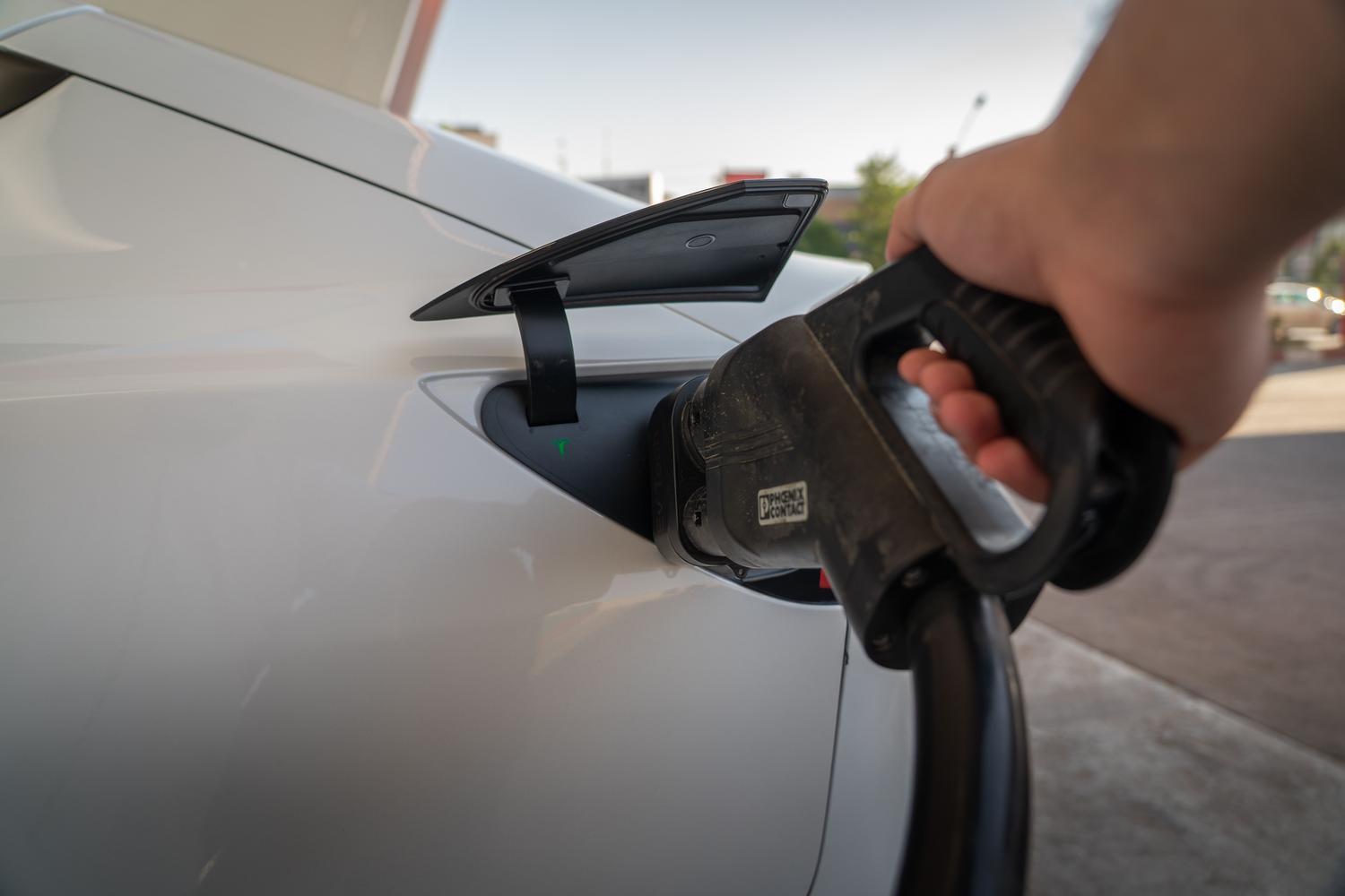Coche eléctrico cargando en una estación, ilustrando la aplicación futura de las baterías cuánticas.