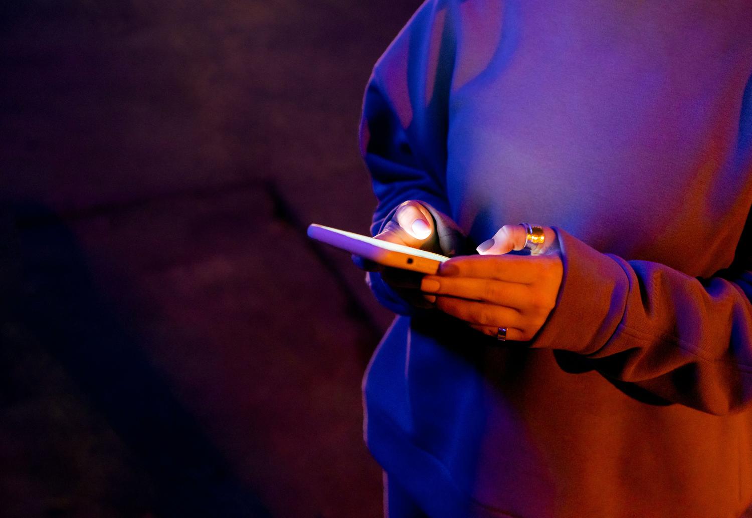 Persona utilizando un smartphone en la oscuridad, iluminada únicamente por la pantalla del móvil, evocando la sensación de escribir mensajes durante la madrugada.