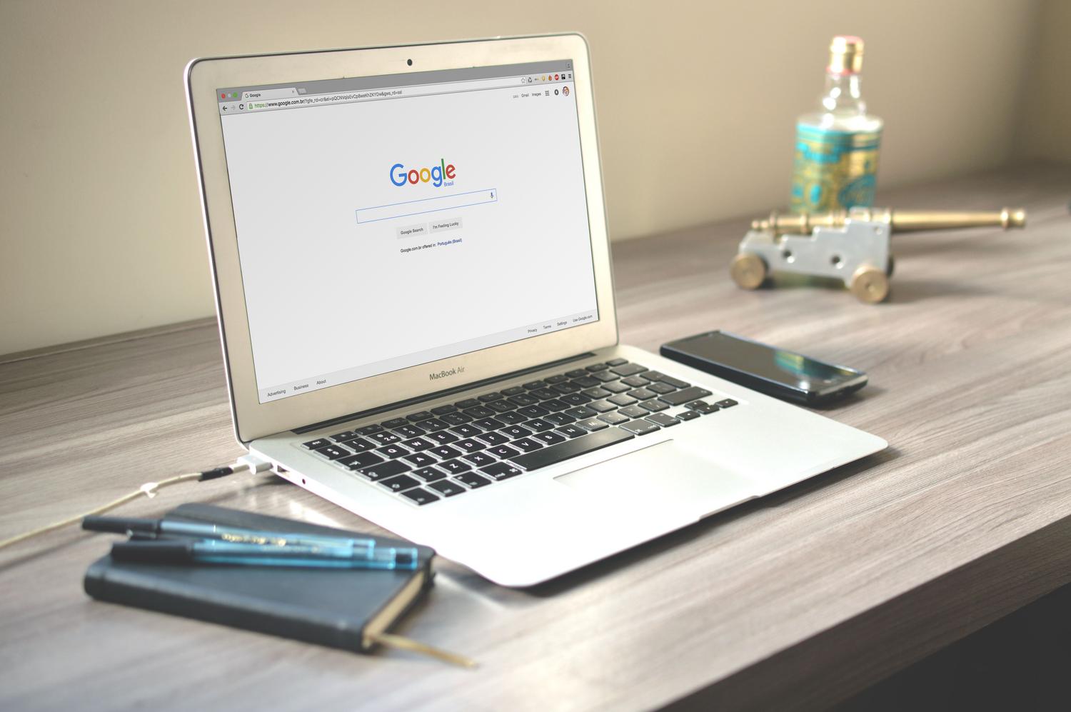 Espacio de trabajo organizado con un portátil mostrando una búsqueda de Google, simbolizando la auditoría de la identidad digital.