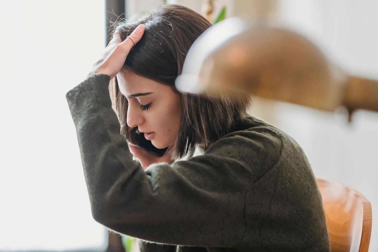 Mujer joven con expresión de angustia y frustración sosteniendo su teléfono móvil, representando el momento del descubrimiento del robo de la cuenta.