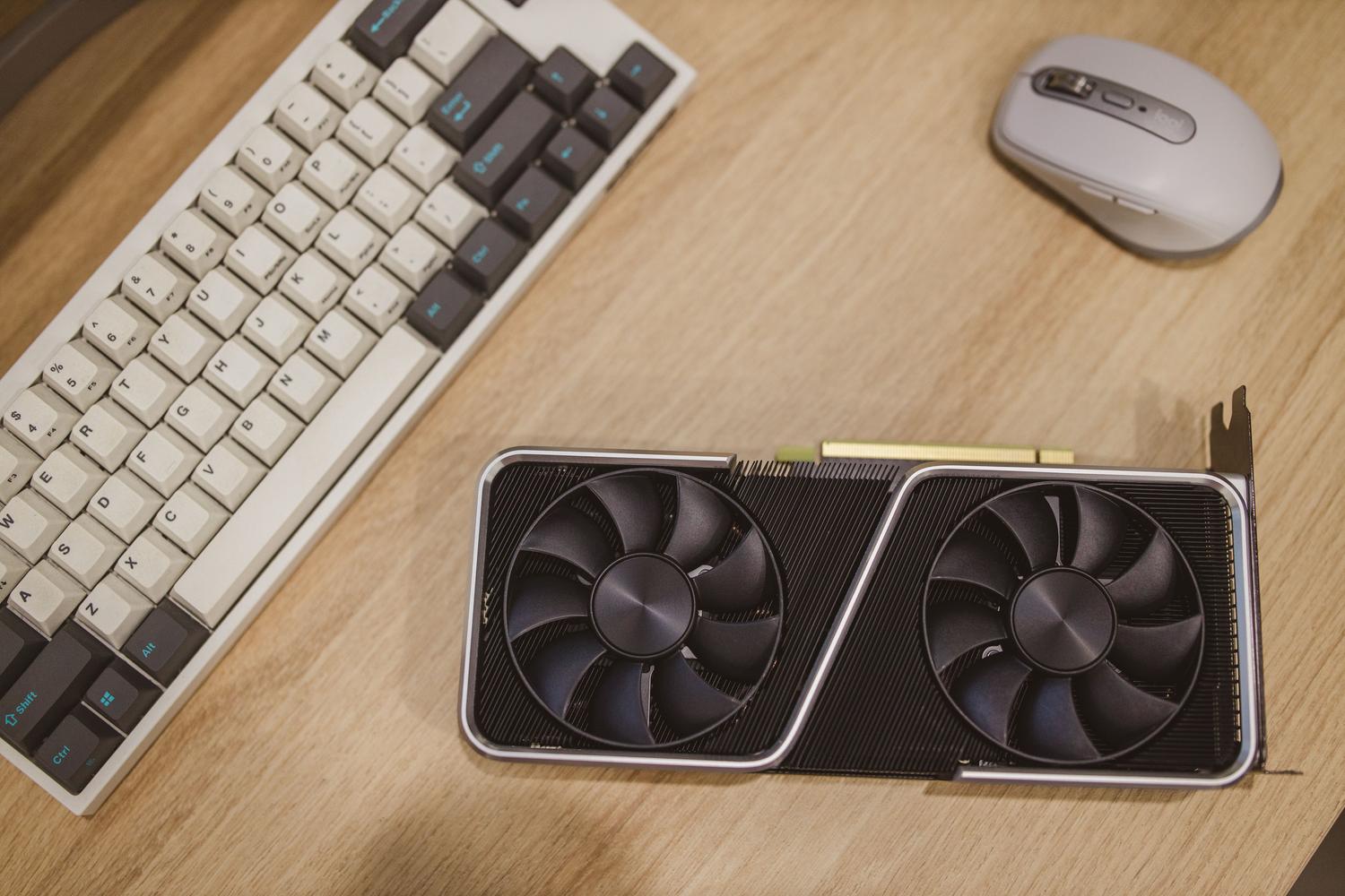 Espacio de trabajo moderno con tarjeta gráfica, teclado y ratón, ideal para ilustrar el uso de GPUs en el sector profesional y diseño creativo.