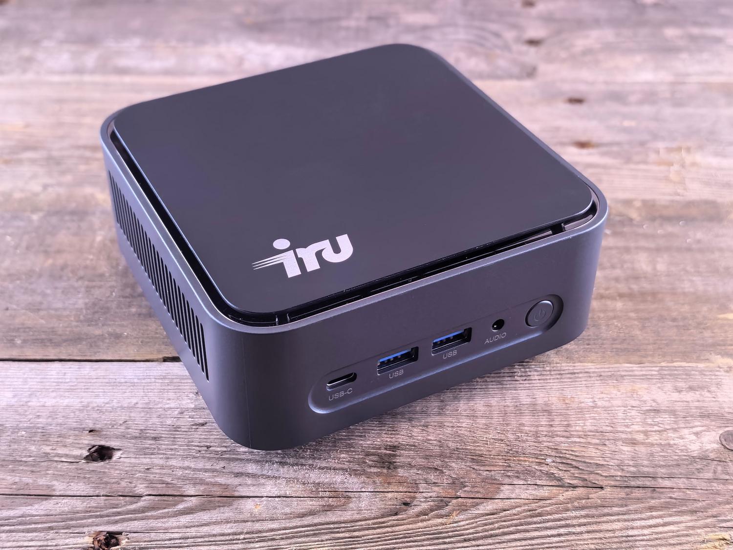 Mini PC compacto sobre una superficie de madera, destacando sus puertos de conectividad y diseño minimalista.