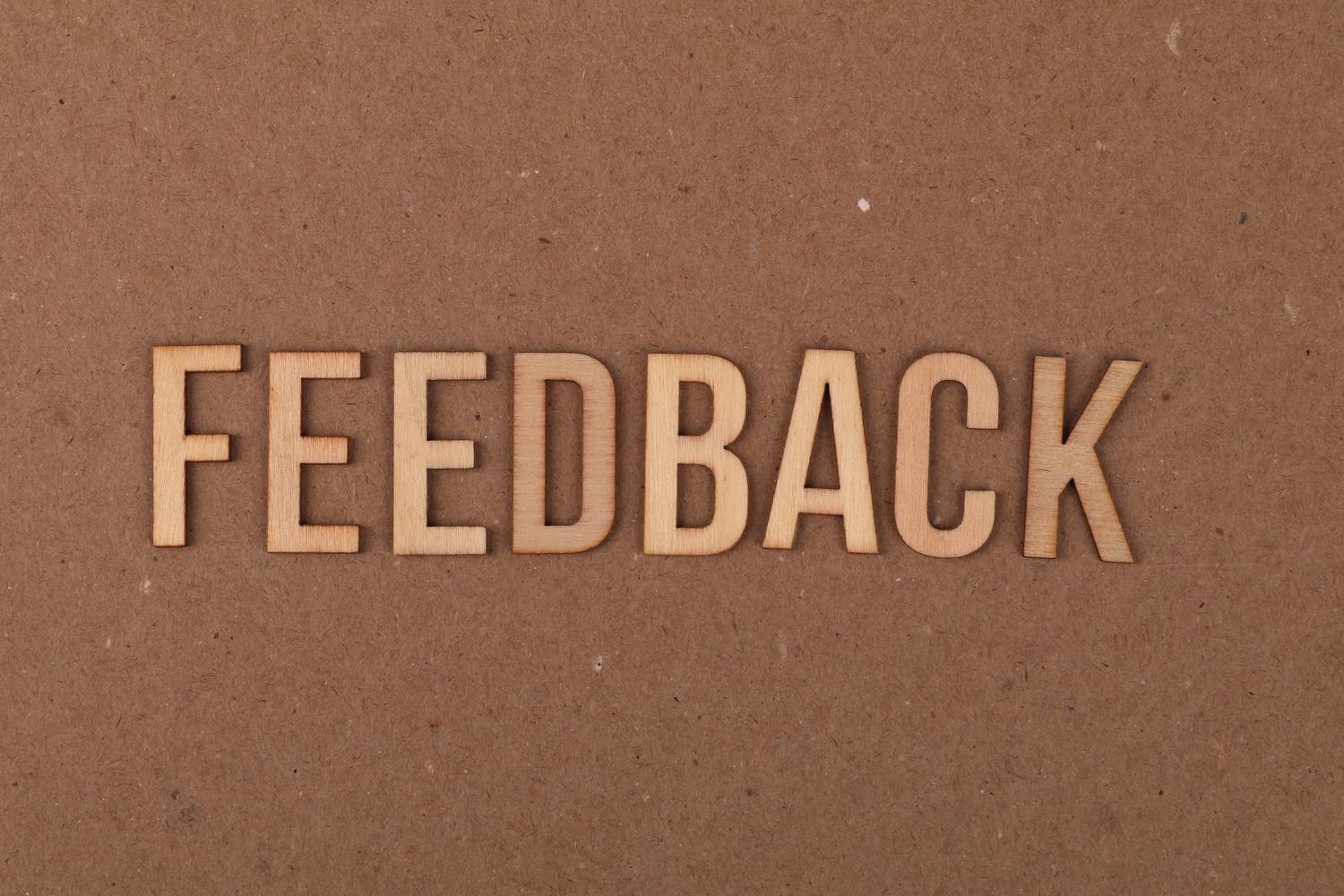Letrero de madera con la palabra "FEEDBACK" sobre un fondo texturizado.