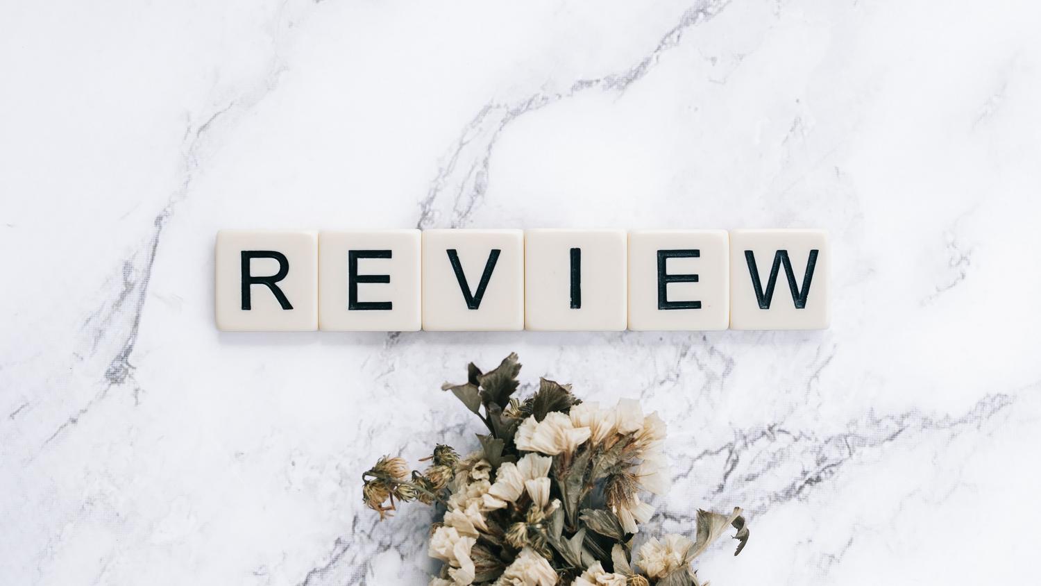 Letras de madera formando la palabra "REVIEW" sobre una superficie de mármol.