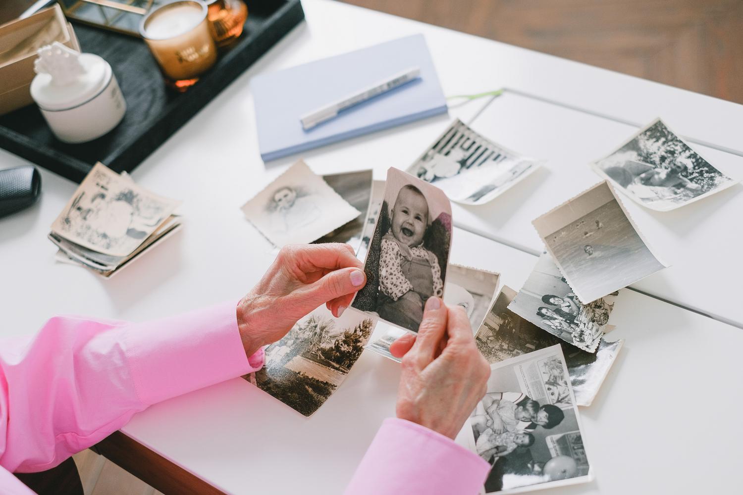 Persona organizando fotografías familiares antiguas sobre una mesa para su posterior digitalización.