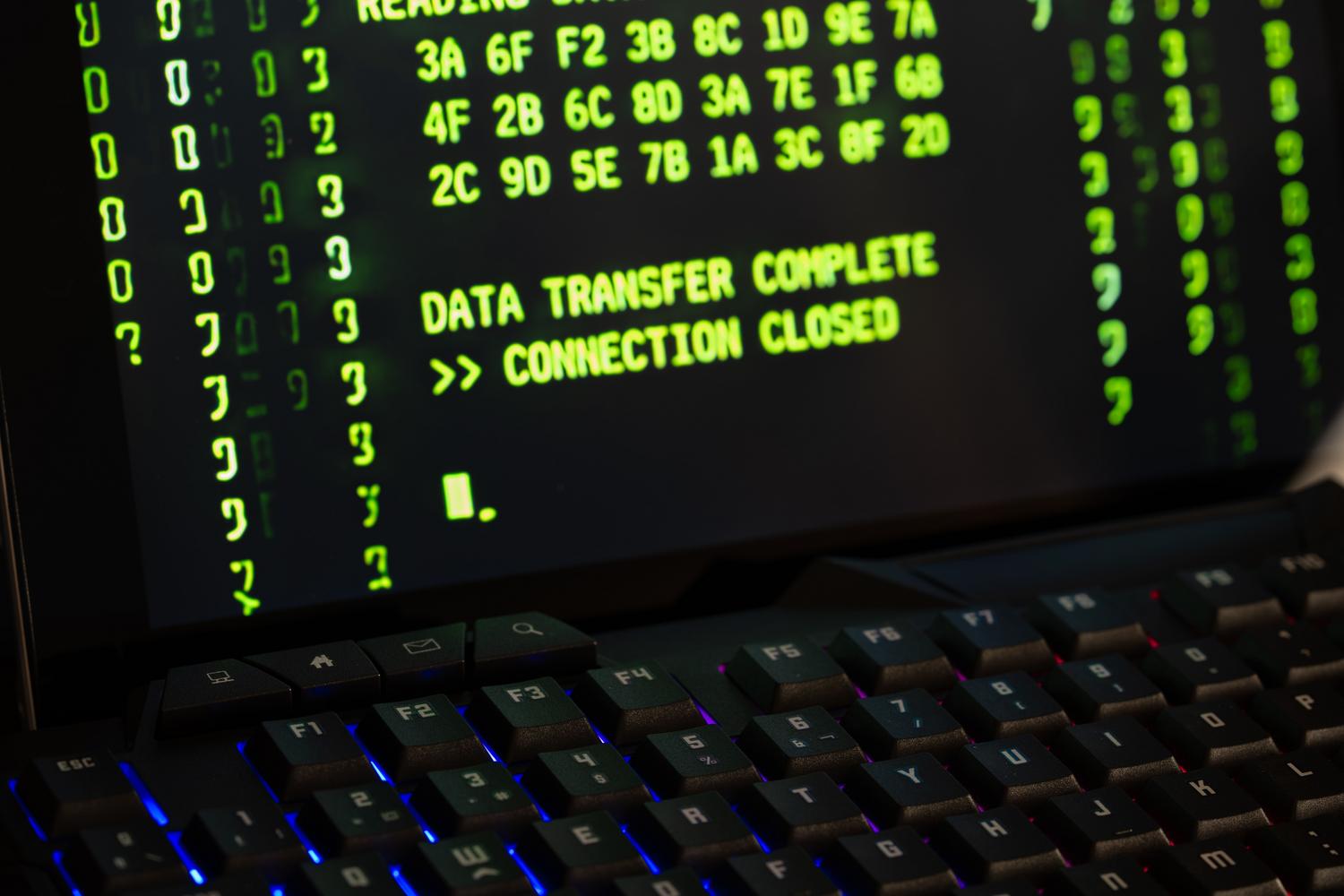 Pantalla de ordenador mostrando el mensaje 'Data Transfer Complete', representando la exfiltración de datos y el robo exitoso de cookies de sesión.