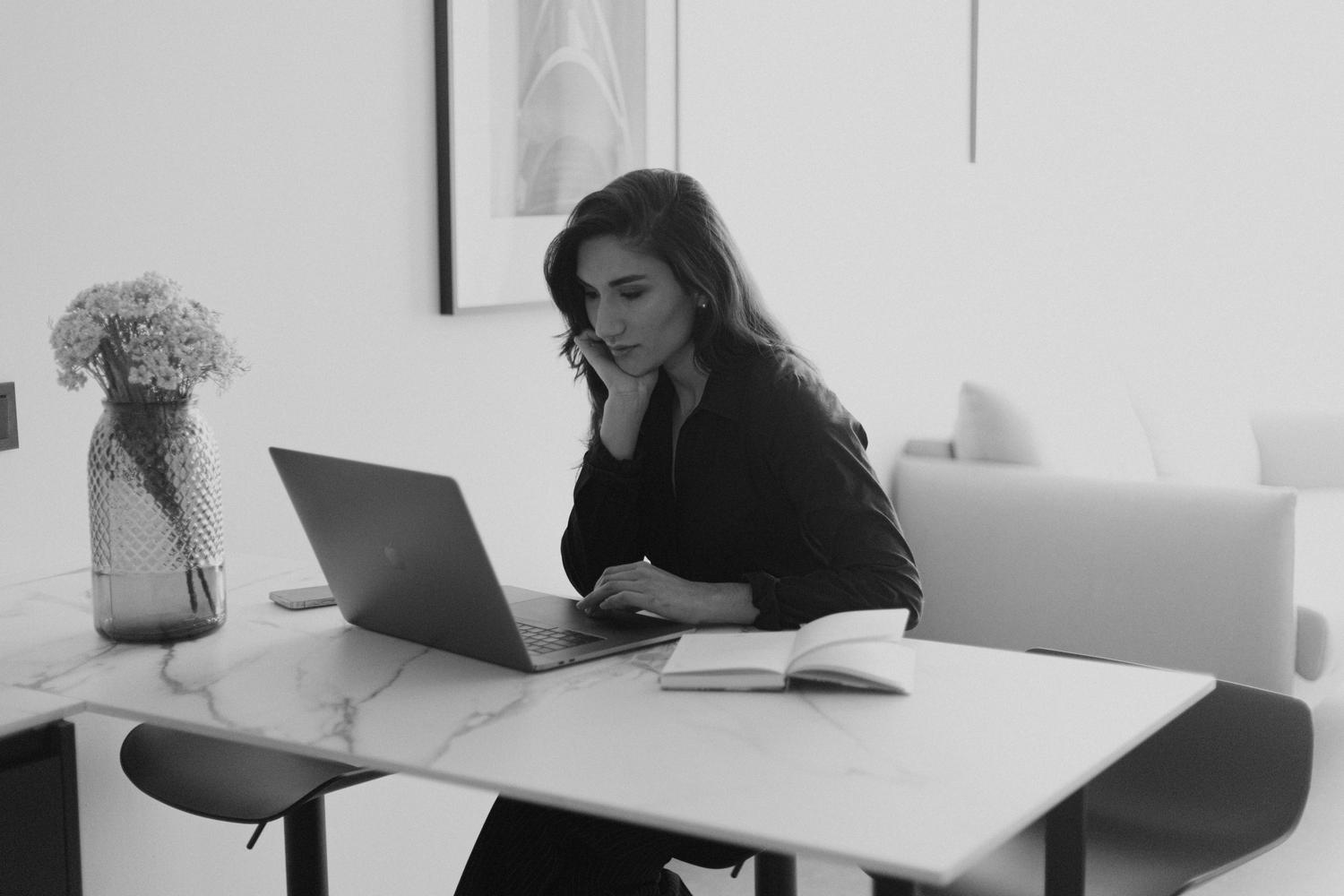 Mujer trabajando con un ordenador portátil en una oficina moderna y minimalista, ideal para teletrabajo.