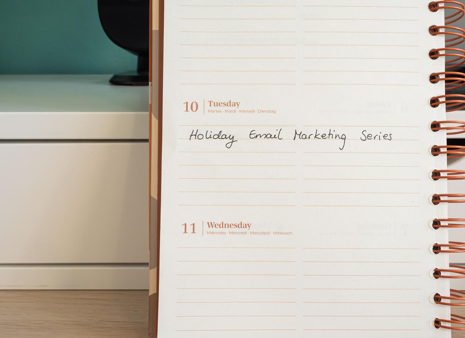 Agenda abierta con una nota manuscrita sobre una serie de campañas de email marketing, ilustrando la planificación estratégica.
